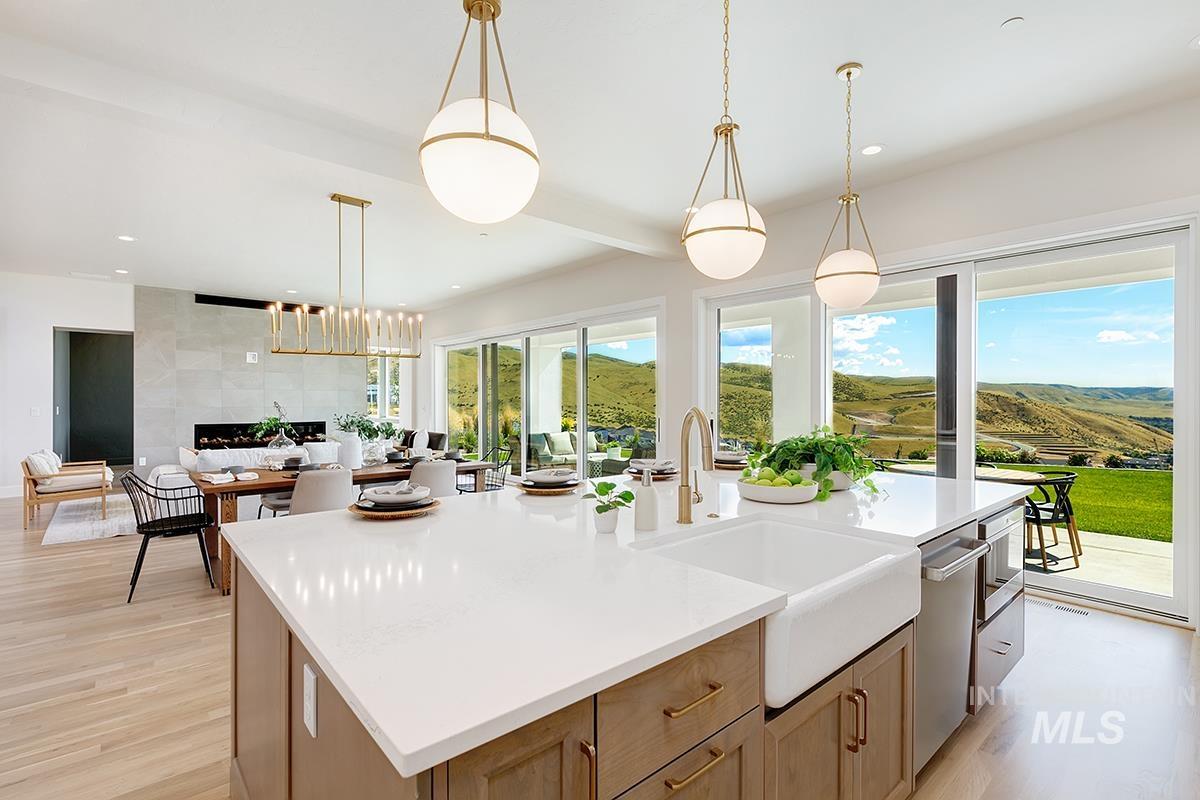 Kitchen with hanging light fixtures, a kitchen island with sink, light brown cabinetry, light wood-style flooring, and recessed lighting
