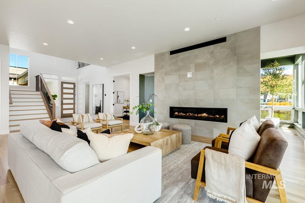 Living area featuring stairs, a tiled fireplace, recessed lighting, light wood finished floors, and tile walls