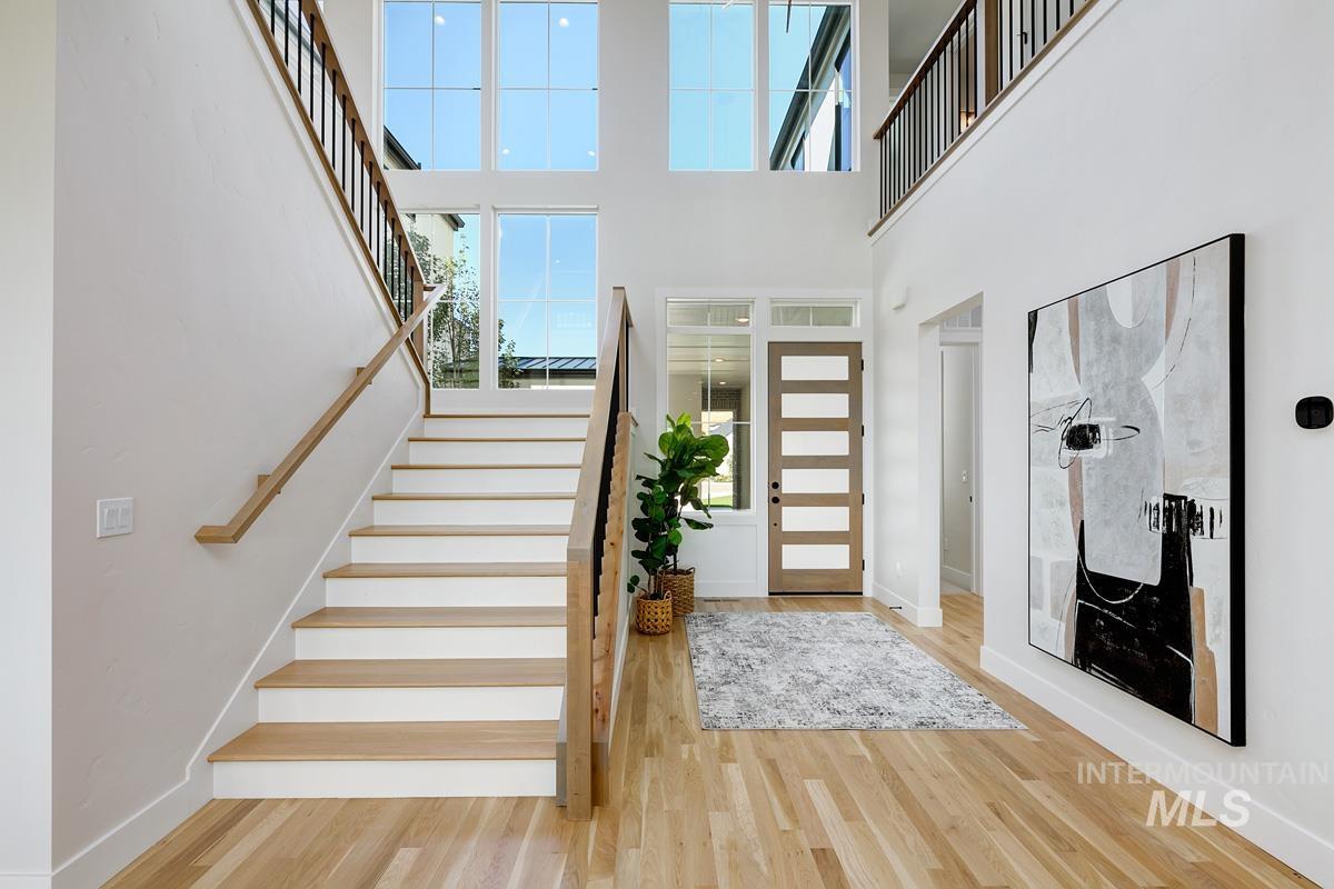 Foyer with stairs, light wood-style floors, and a towering ceiling