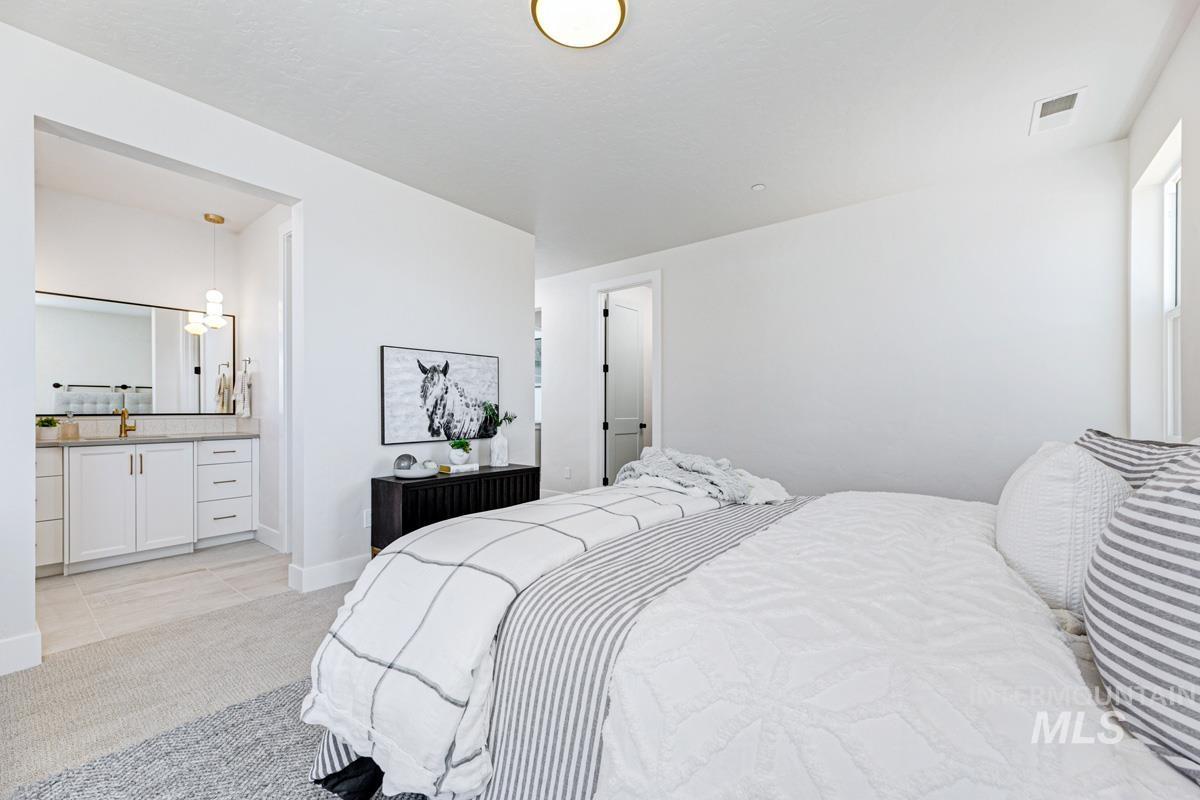 Bedroom with light colored carpet, light tile patterned floors, and ensuite bathroom
