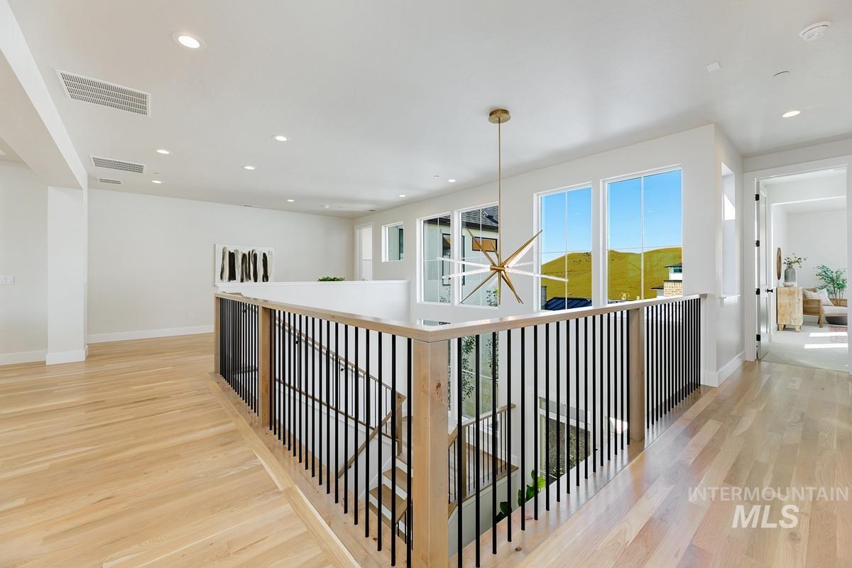 Corridor with light wood-style floors, recessed lighting, a chandelier, and an upstairs landing