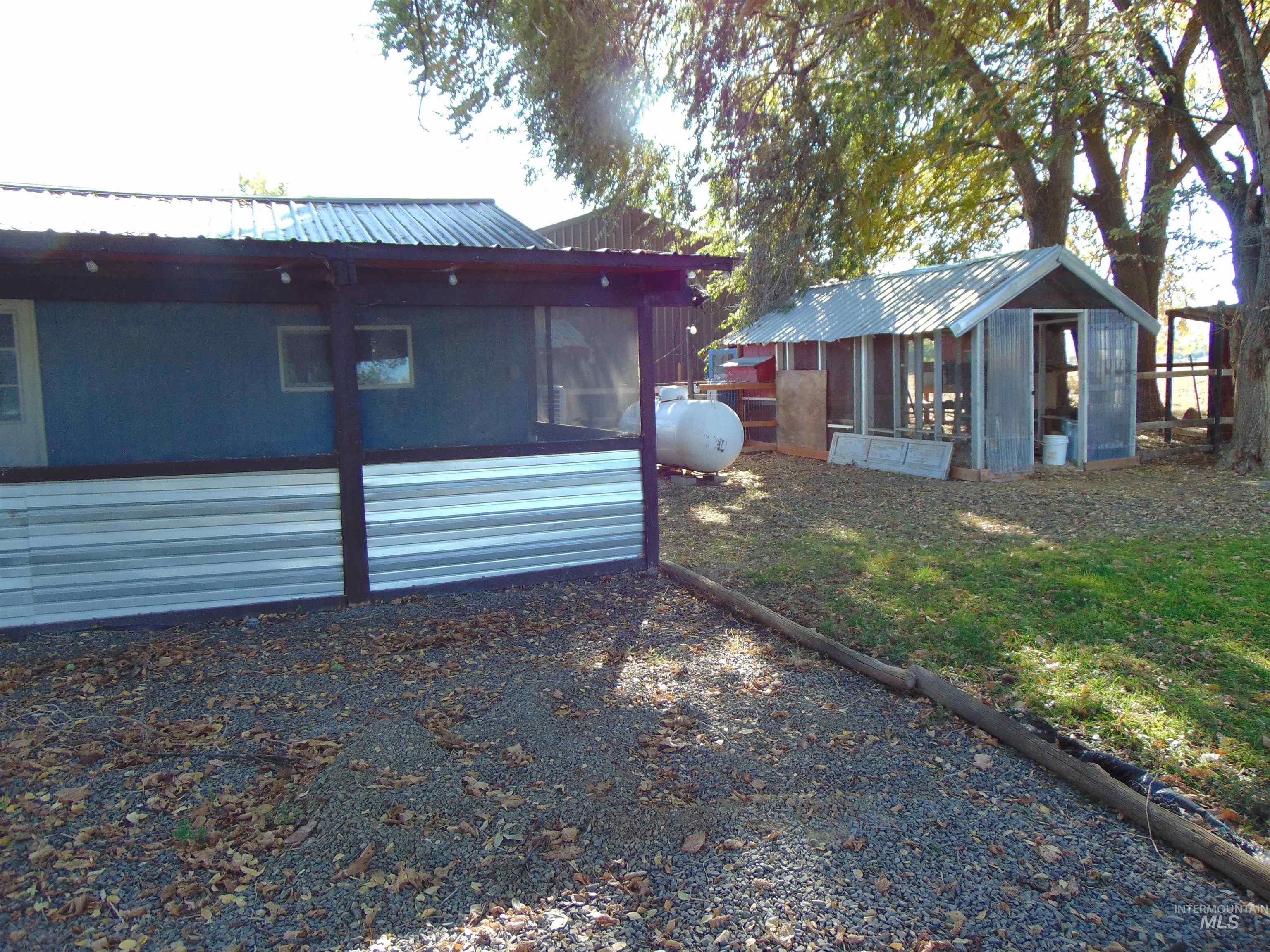 Back of property featuring a metal roof, a sunroom, and an outbuilding