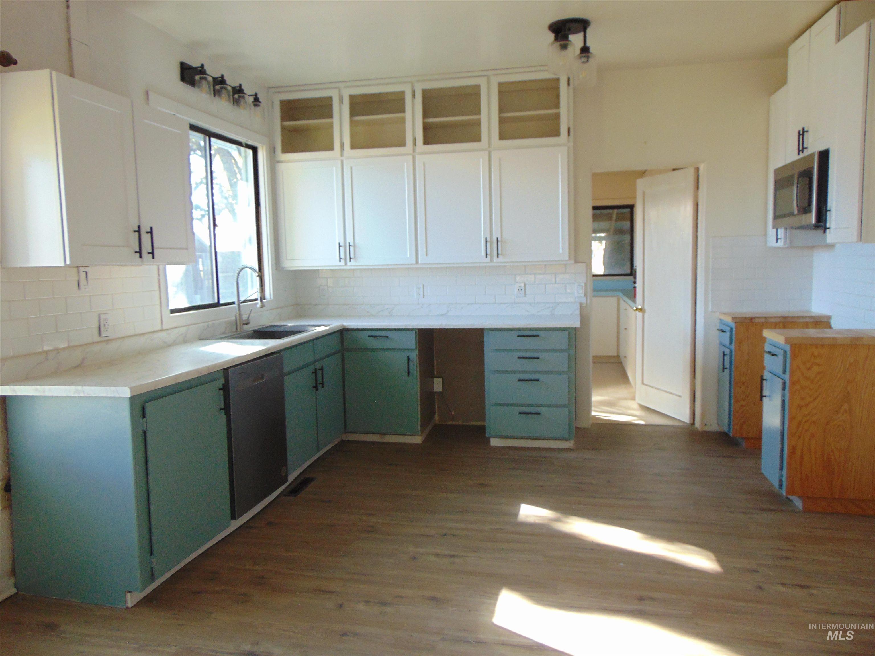 Kitchen with green cabinetry, white cabinetry, and dark wood-type flooring