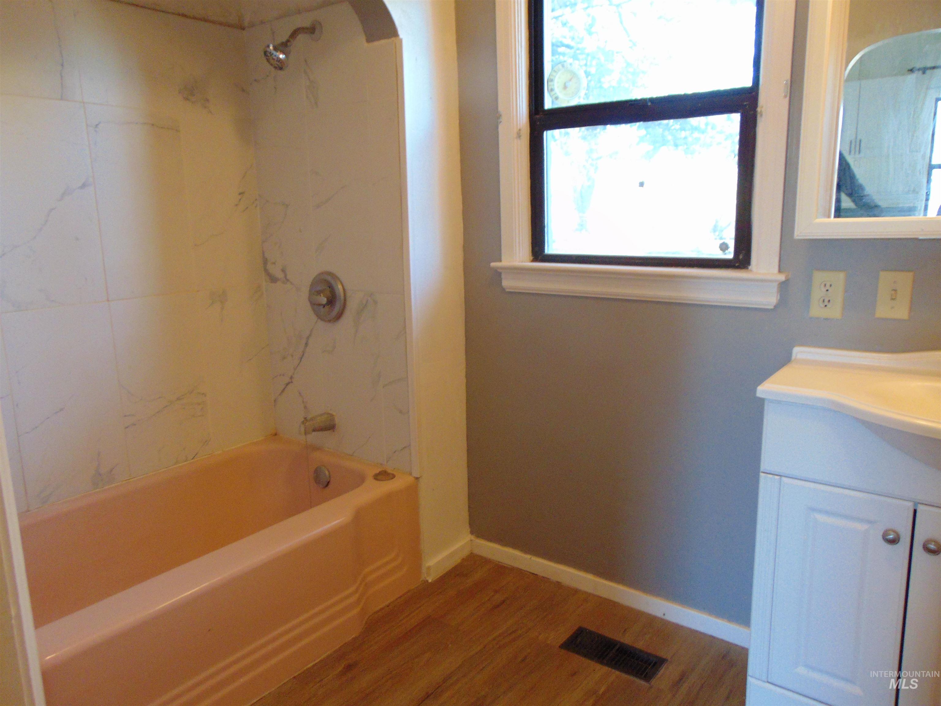 Bathroom featuring shower / bath combination, vanity, and light wood-style floors