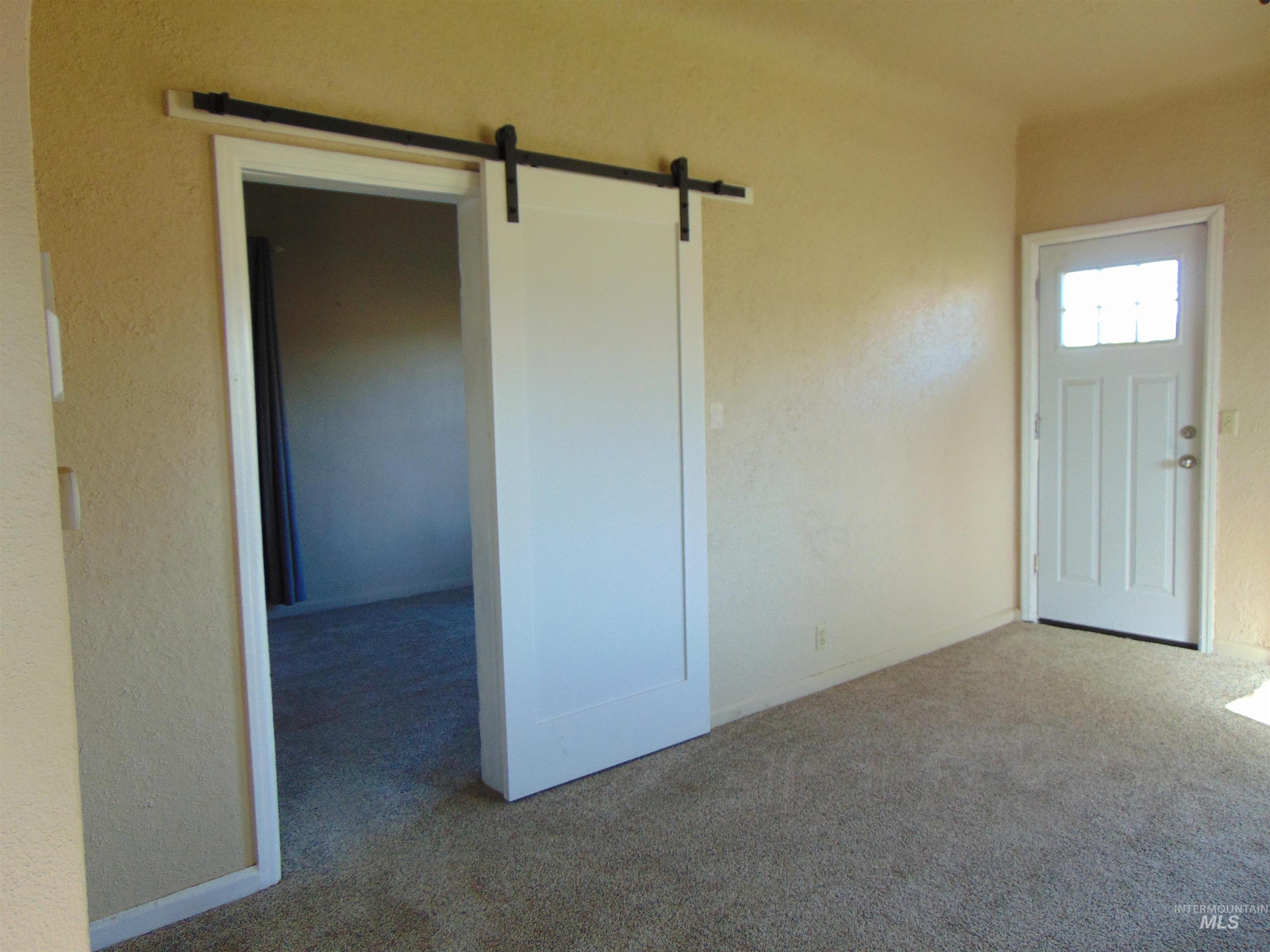 Entrance foyer featuring a barn door, carpet floors, and a textured wall