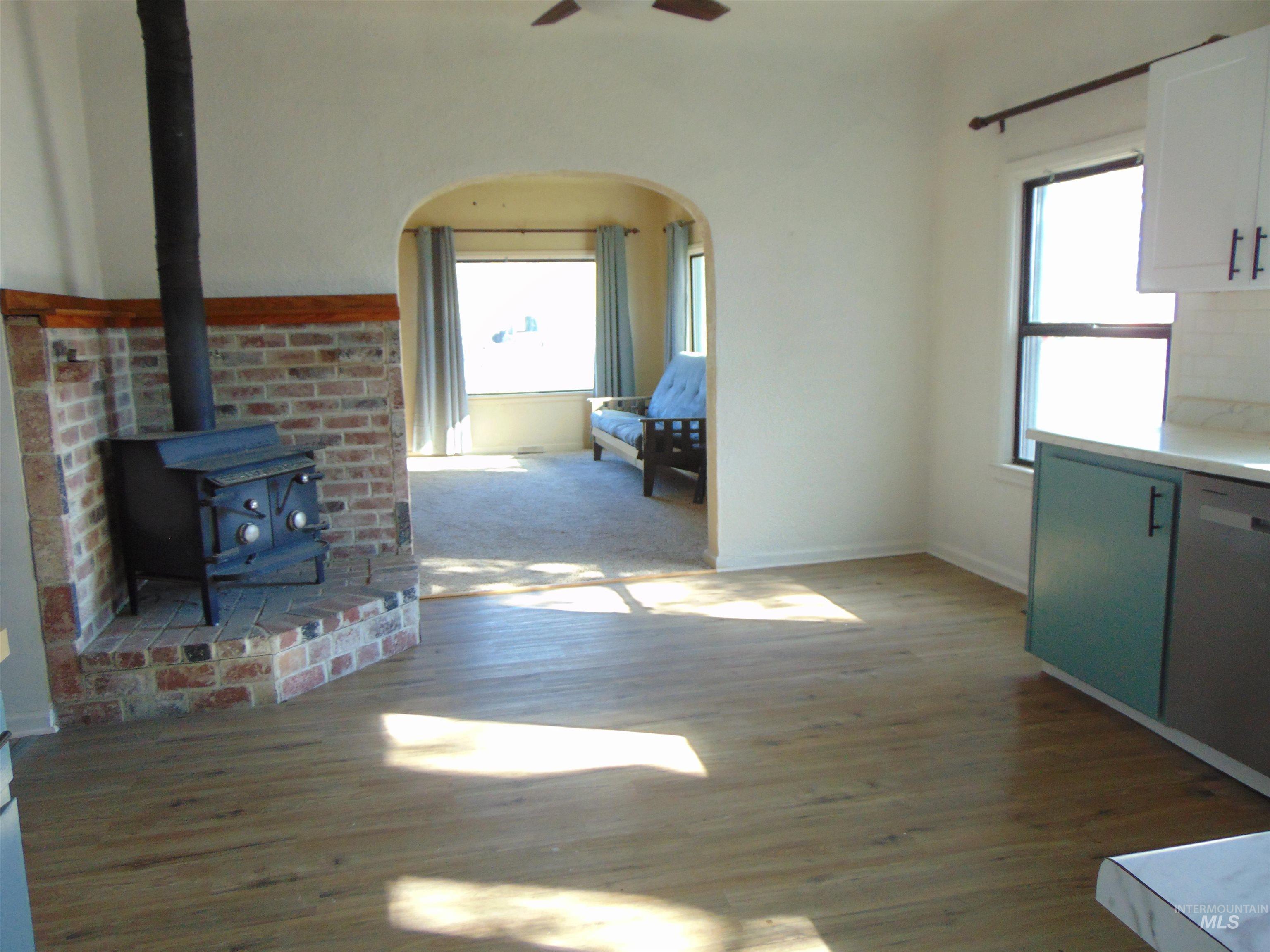 Unfurnished living room featuring a wood stove, light wood finished floors, and ceiling fan