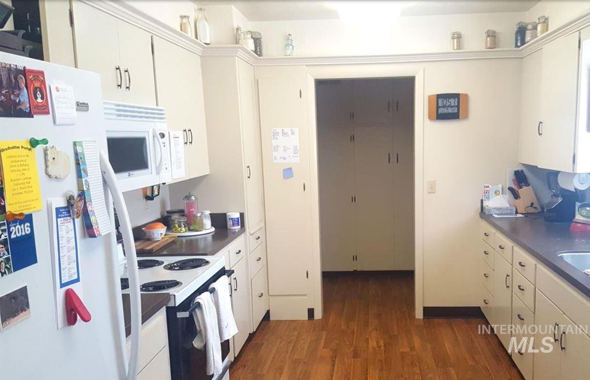Kitchen featuring white appliances, dark wood-style floors, and white cabinets