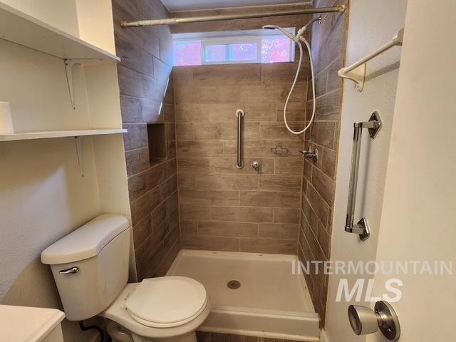 Full bath featuring a shower stall and toilet