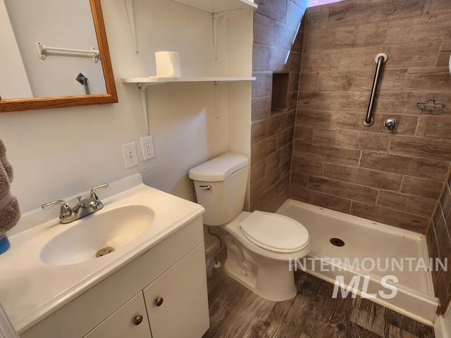 Full bath with vanity, dark wood-style floors, and a shower stall