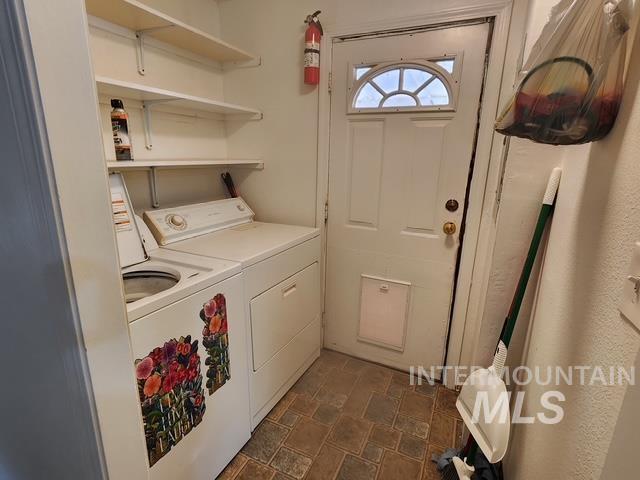 Laundry room with washer and clothes dryer and stone finish floors