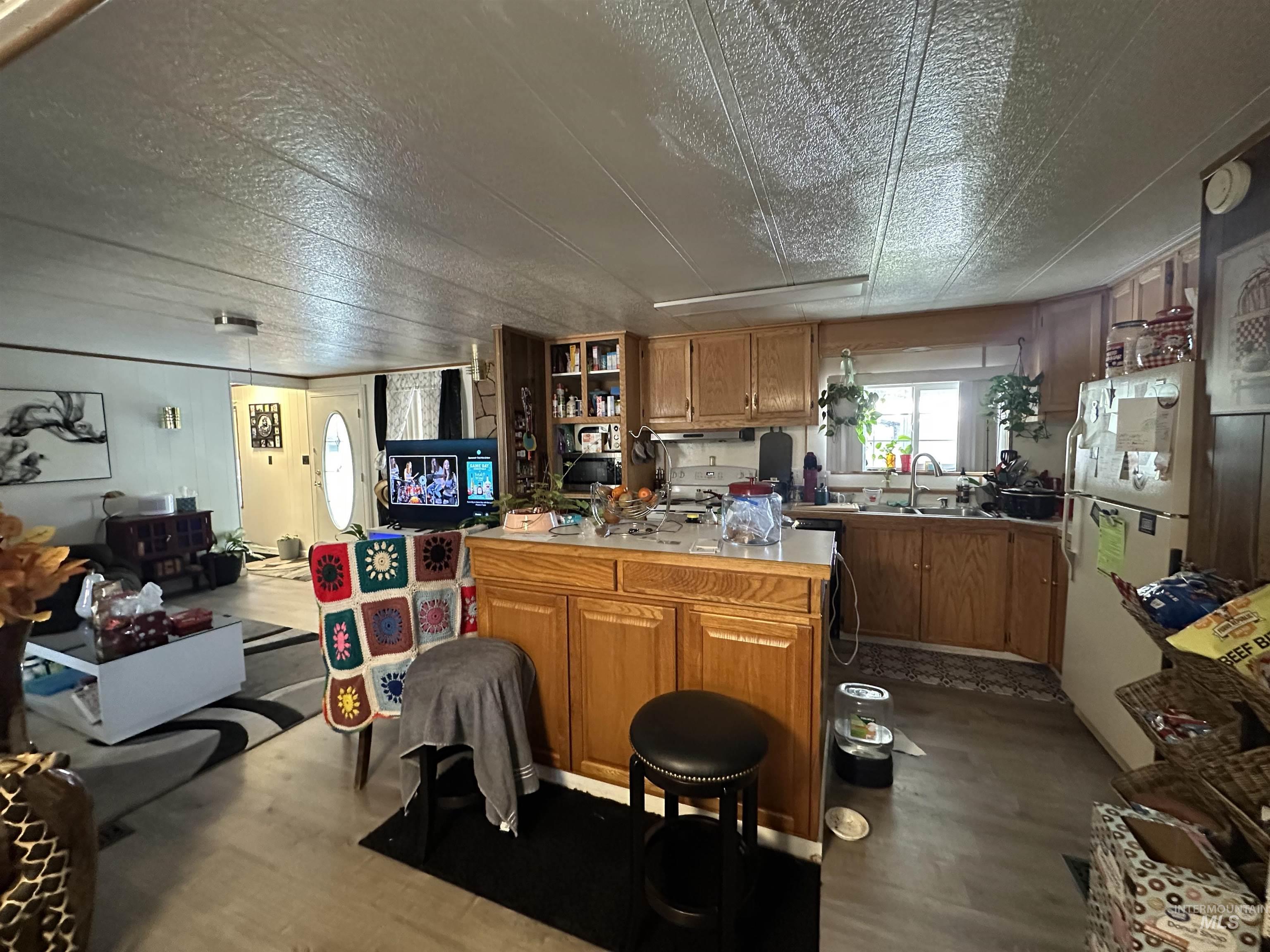 Kitchen featuring dark wood-style floors, light countertops, brown cabinets, freestanding refrigerator, and stove