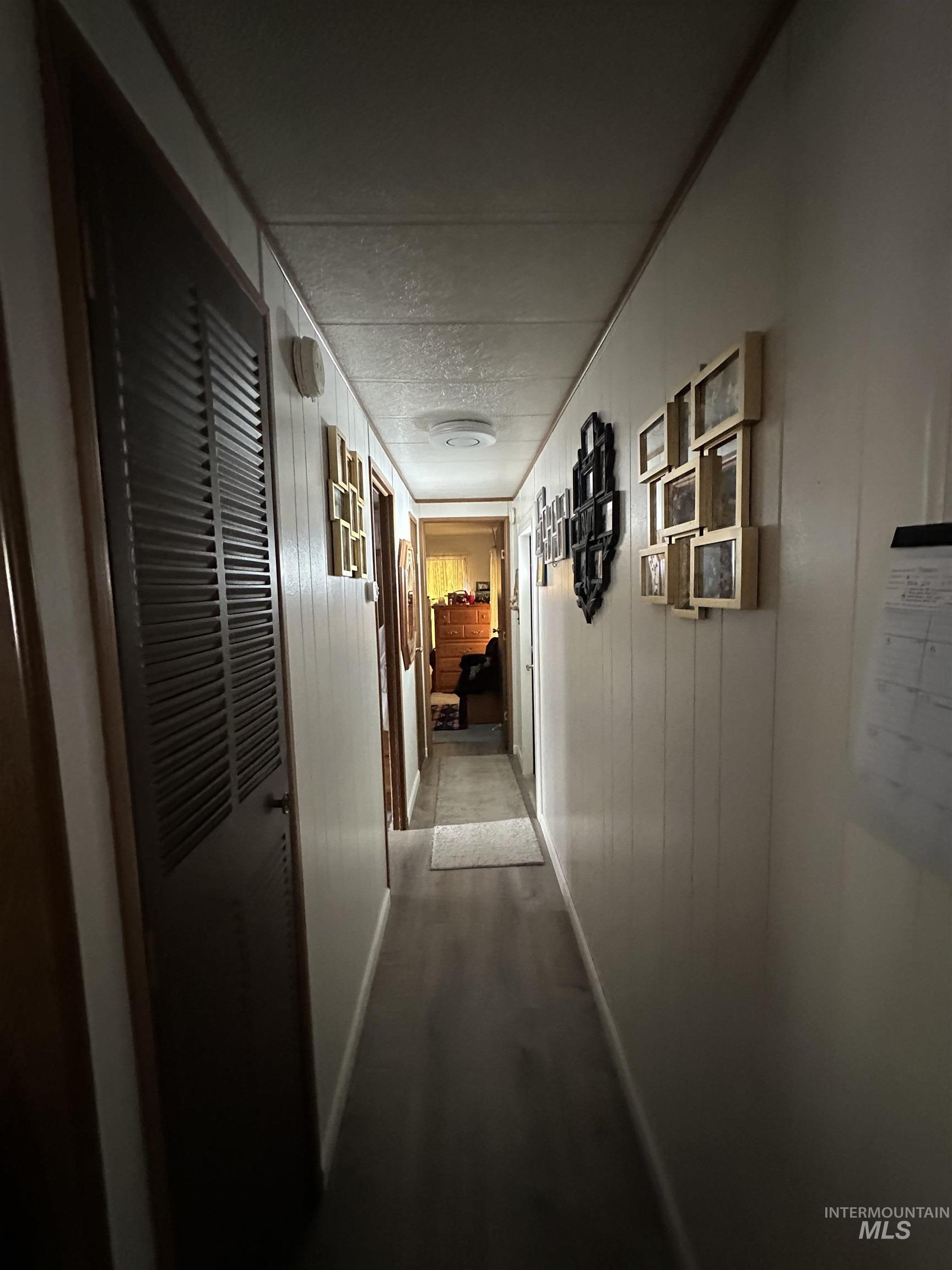 Hallway featuring dark wood finished floors, a heating unit, wood walls, and a textured ceiling