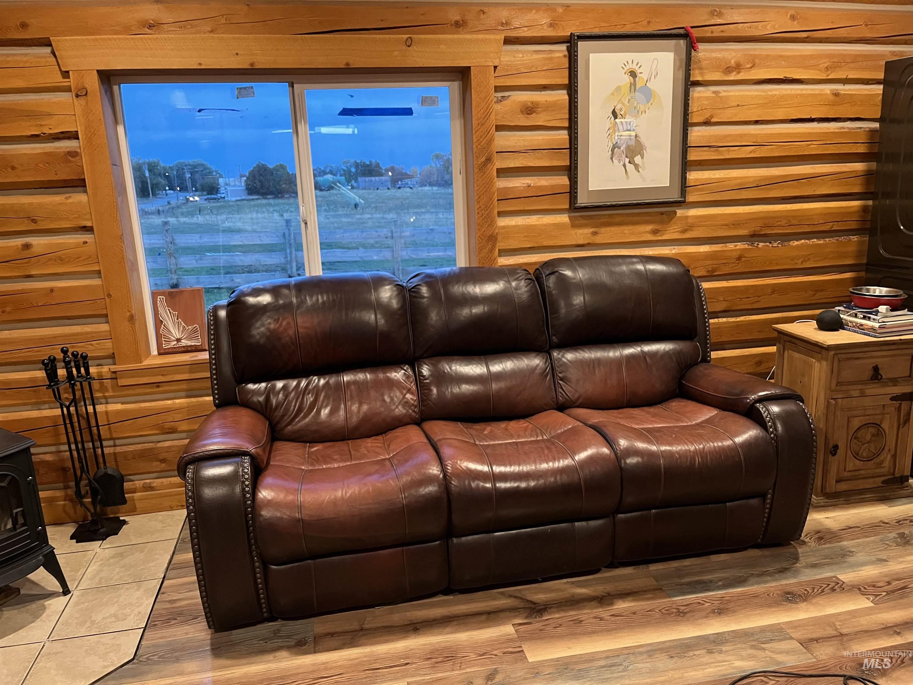 Home theater room featuring rustic walls, a wood stove, and wood finished floors