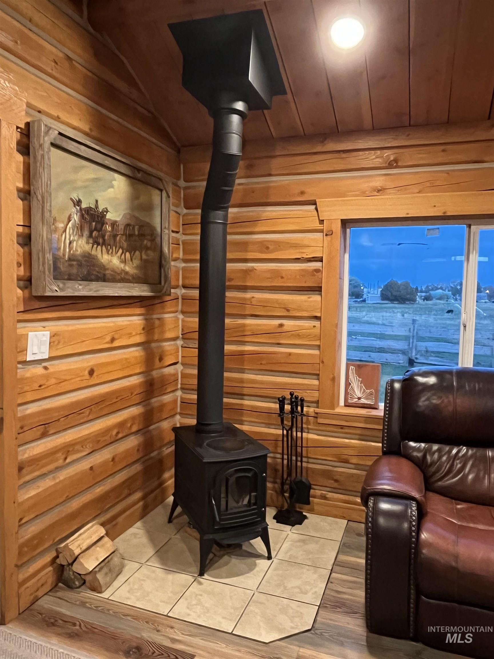 Living room with a wood stove, wood ceiling, wood finished floors, and vaulted ceiling