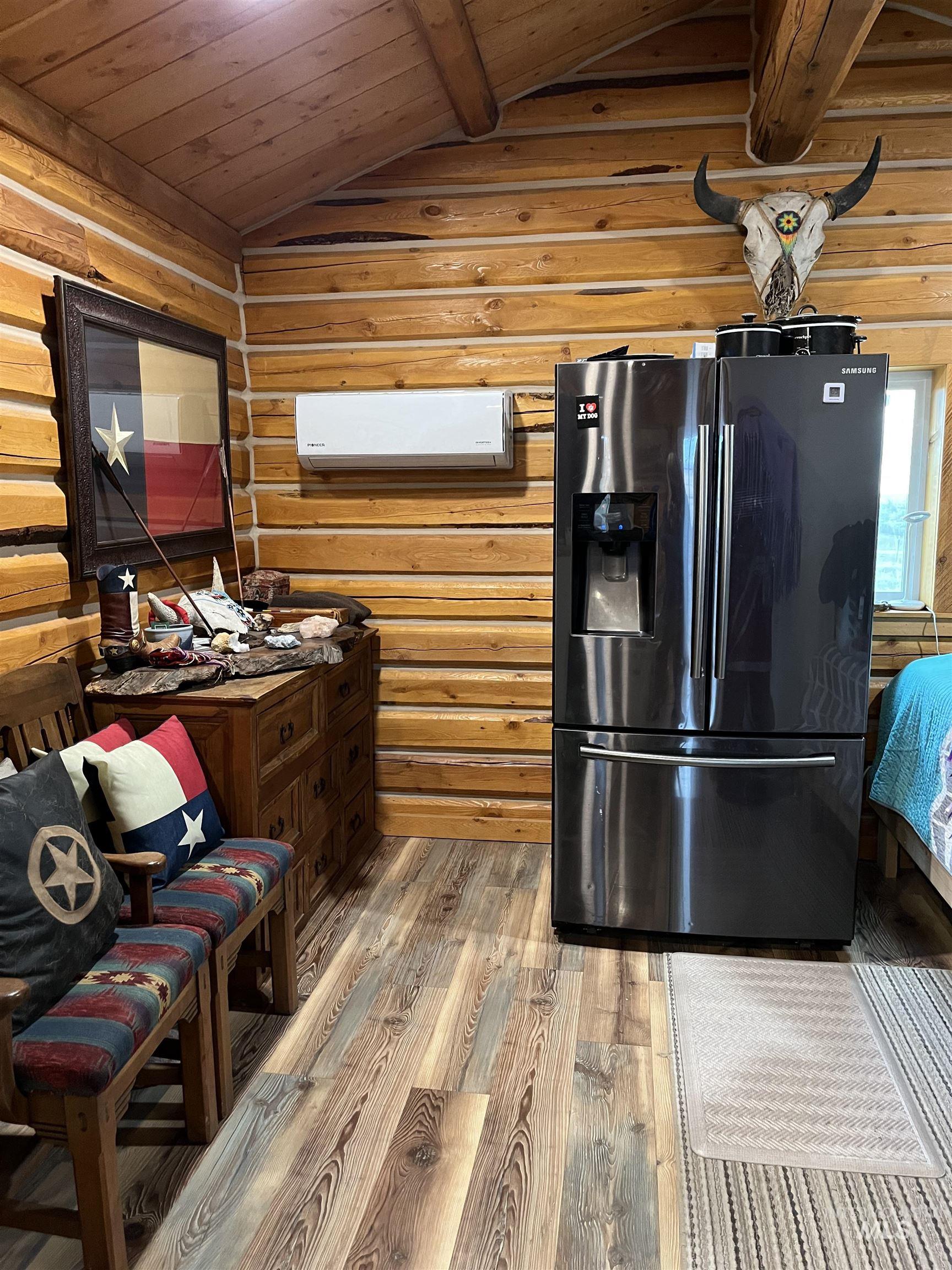 Kitchen featuring fridge with ice dispenser, light wood finished floors, wooden ceiling, and wooden walls