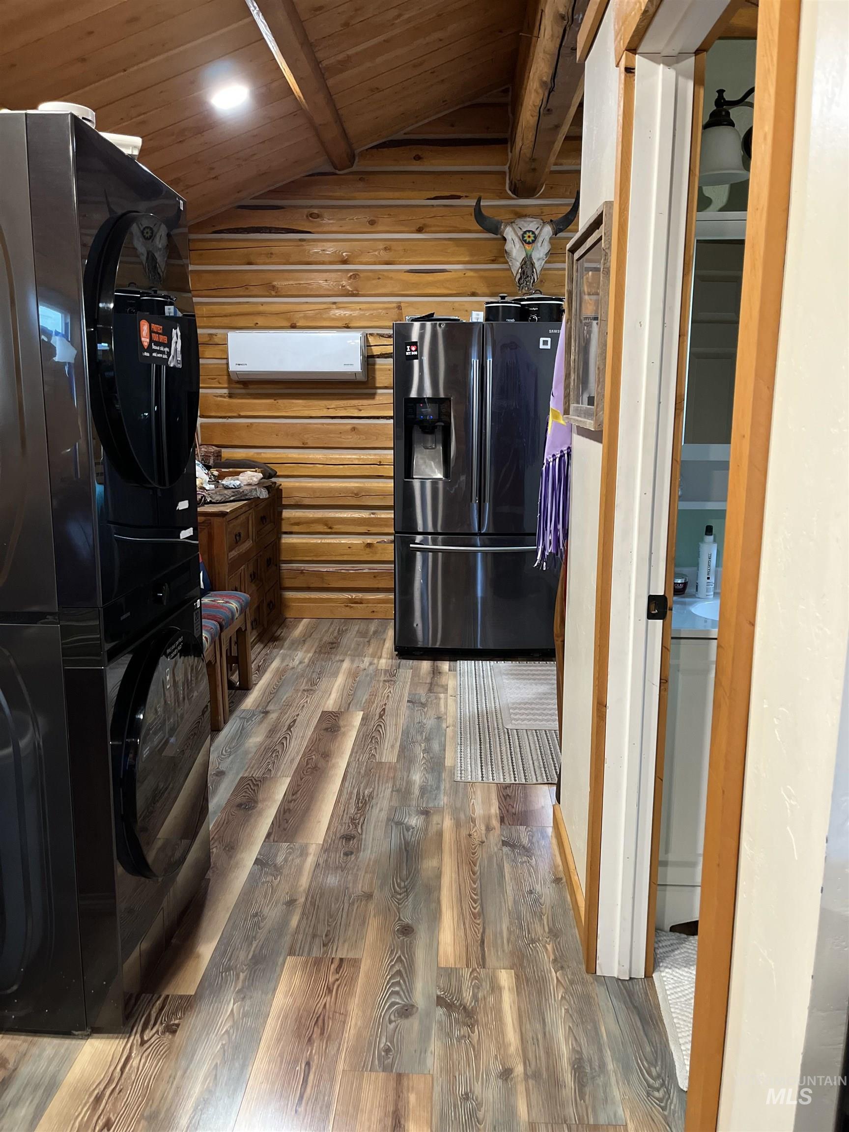 Kitchen with wood finished floors, refrigerator with ice dispenser, wooden ceiling, black refrigerator, and rustic walls