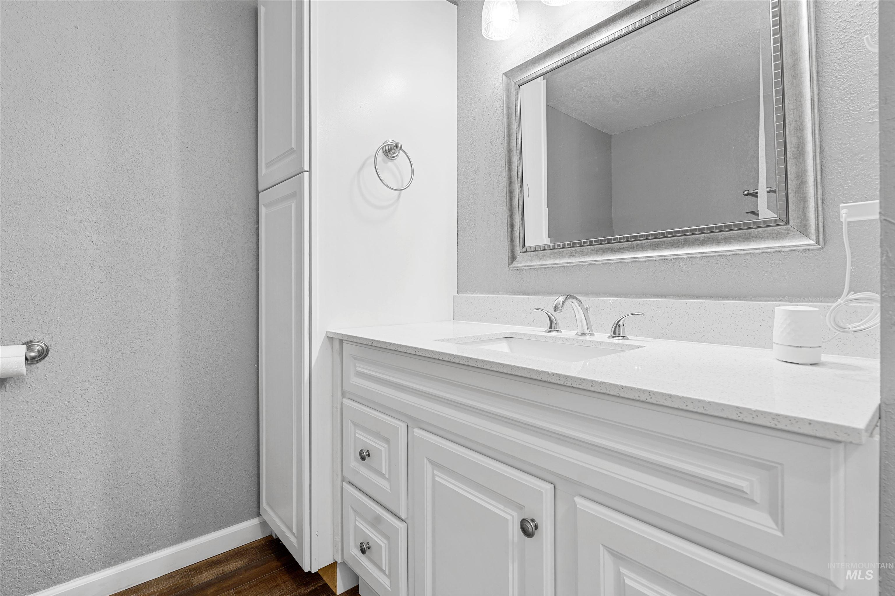 Bathroom featuring a textured wall, vanity, and dark wood finished floors