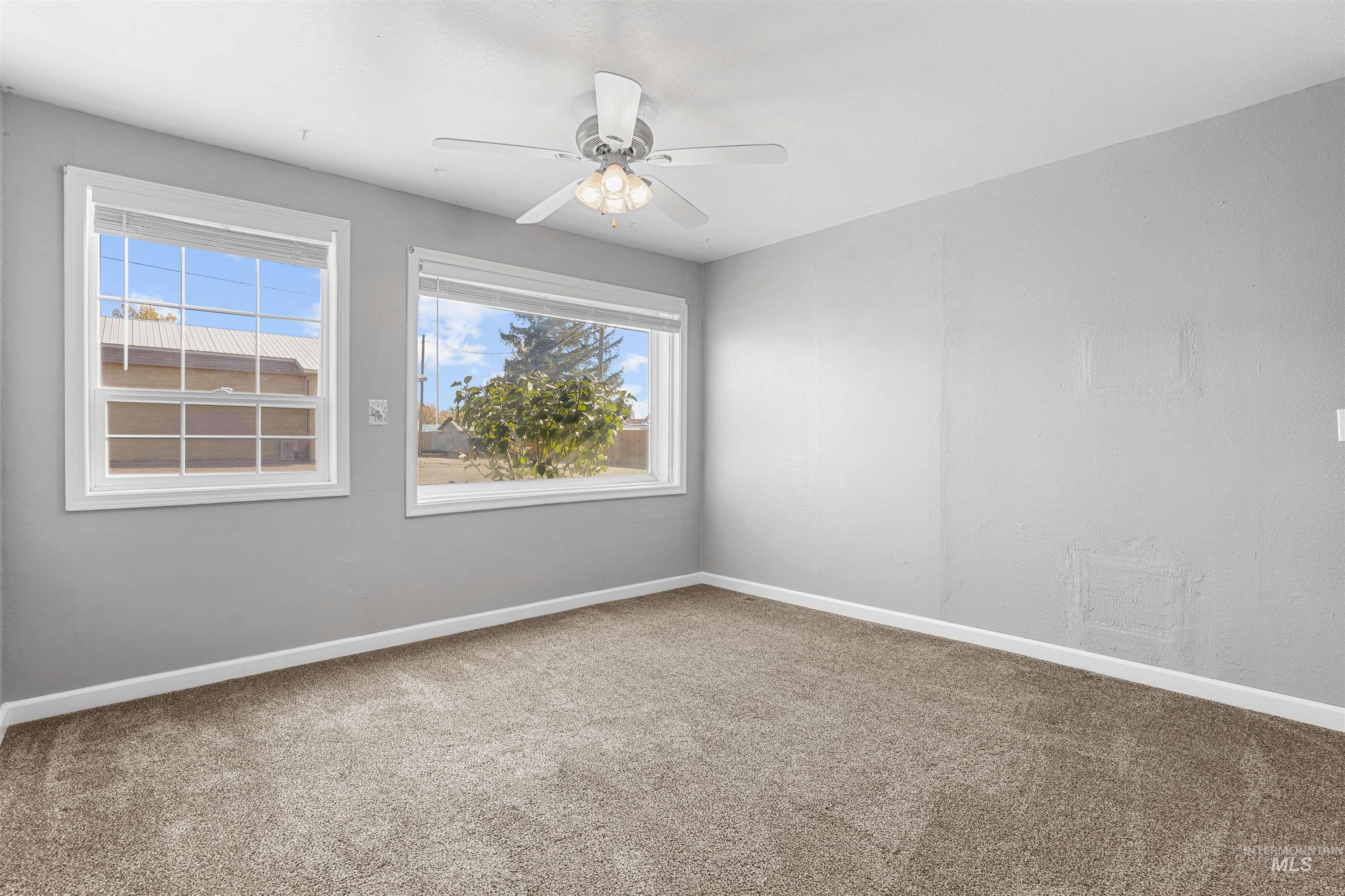 Carpeted empty room featuring healthy amount of natural light and ceiling fan