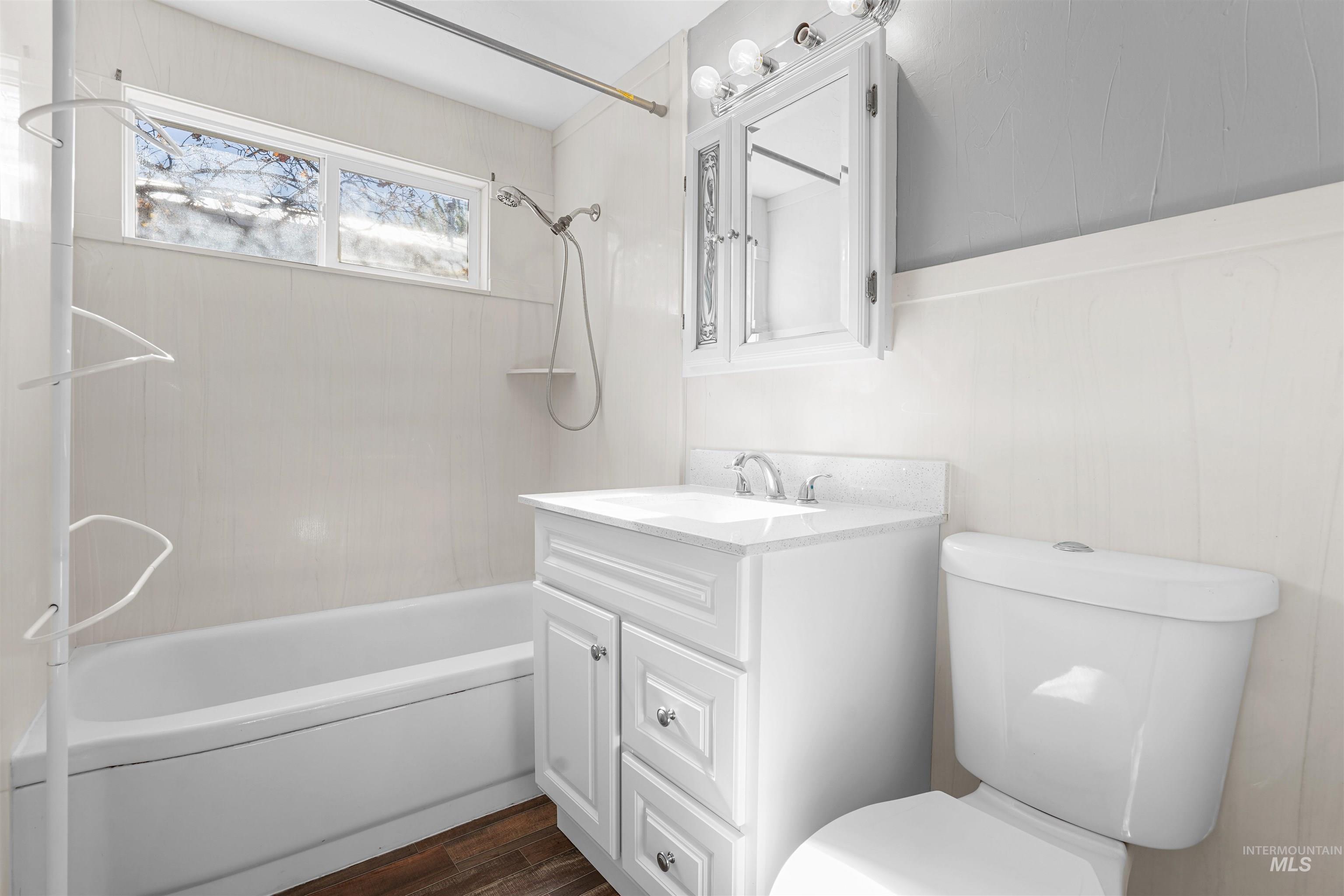 Bathroom featuring vanity, shower / bath combination, and dark wood-style floors