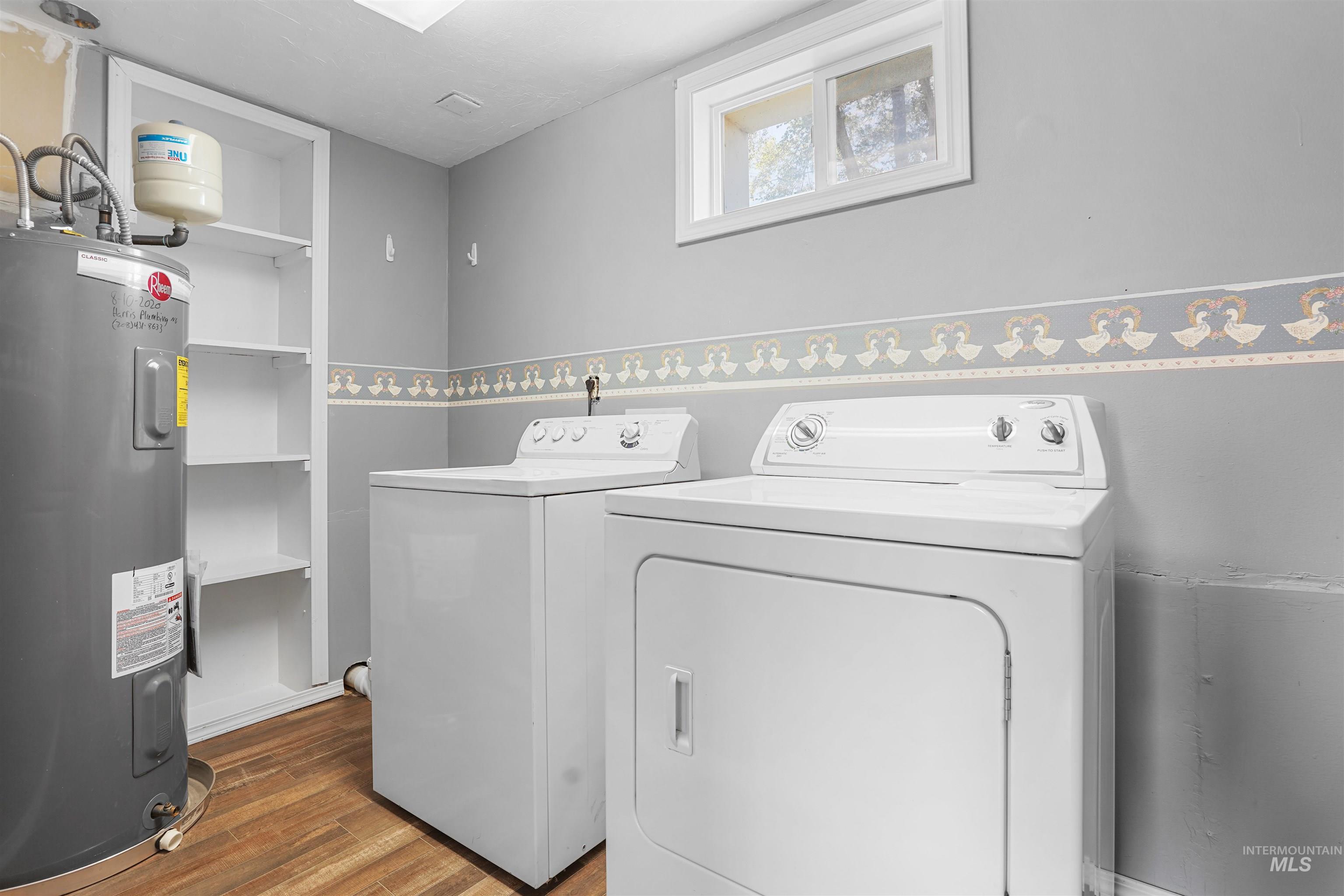 Washroom featuring electric water heater, dark wood-type flooring, and separate washer and dryer