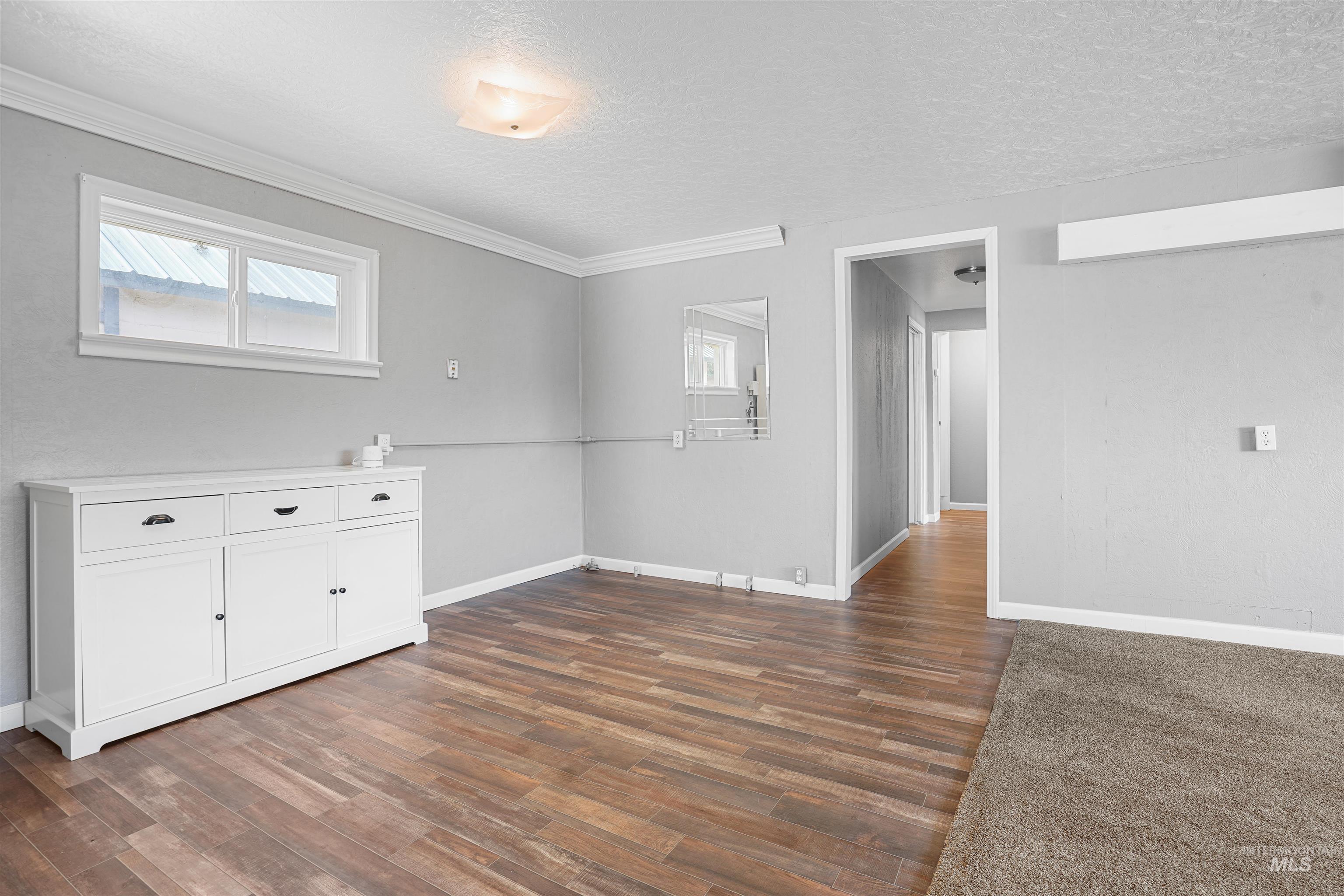 Empty room with a textured ceiling and dark wood-style flooring