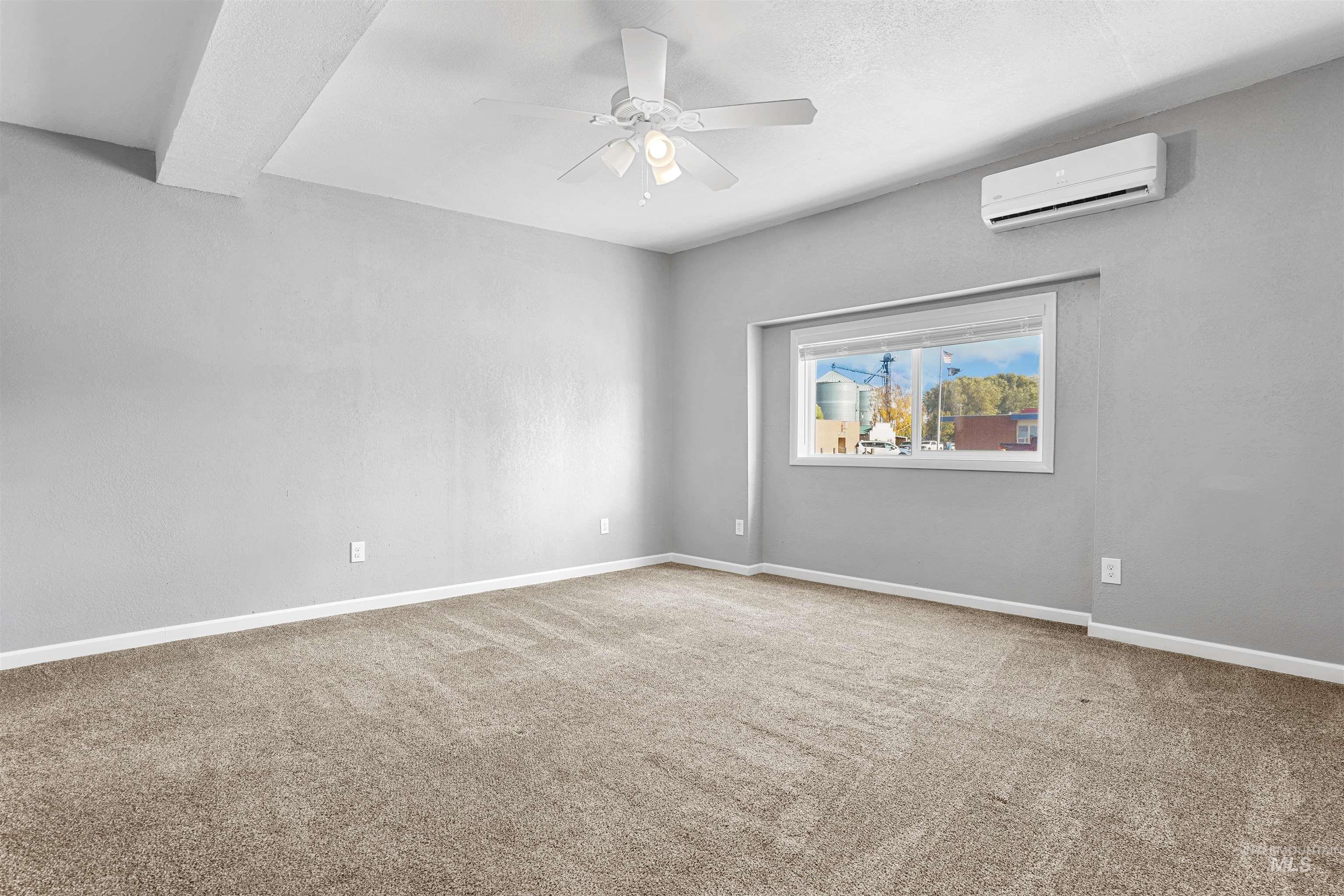 Empty room with light carpet, ceiling fan, and a wall mounted AC