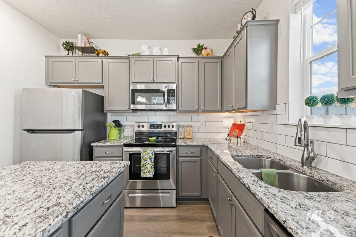 Kitchen with gray cabinets, stainless steel appliances, backsplash, plenty of natural light, and a textured ceiling