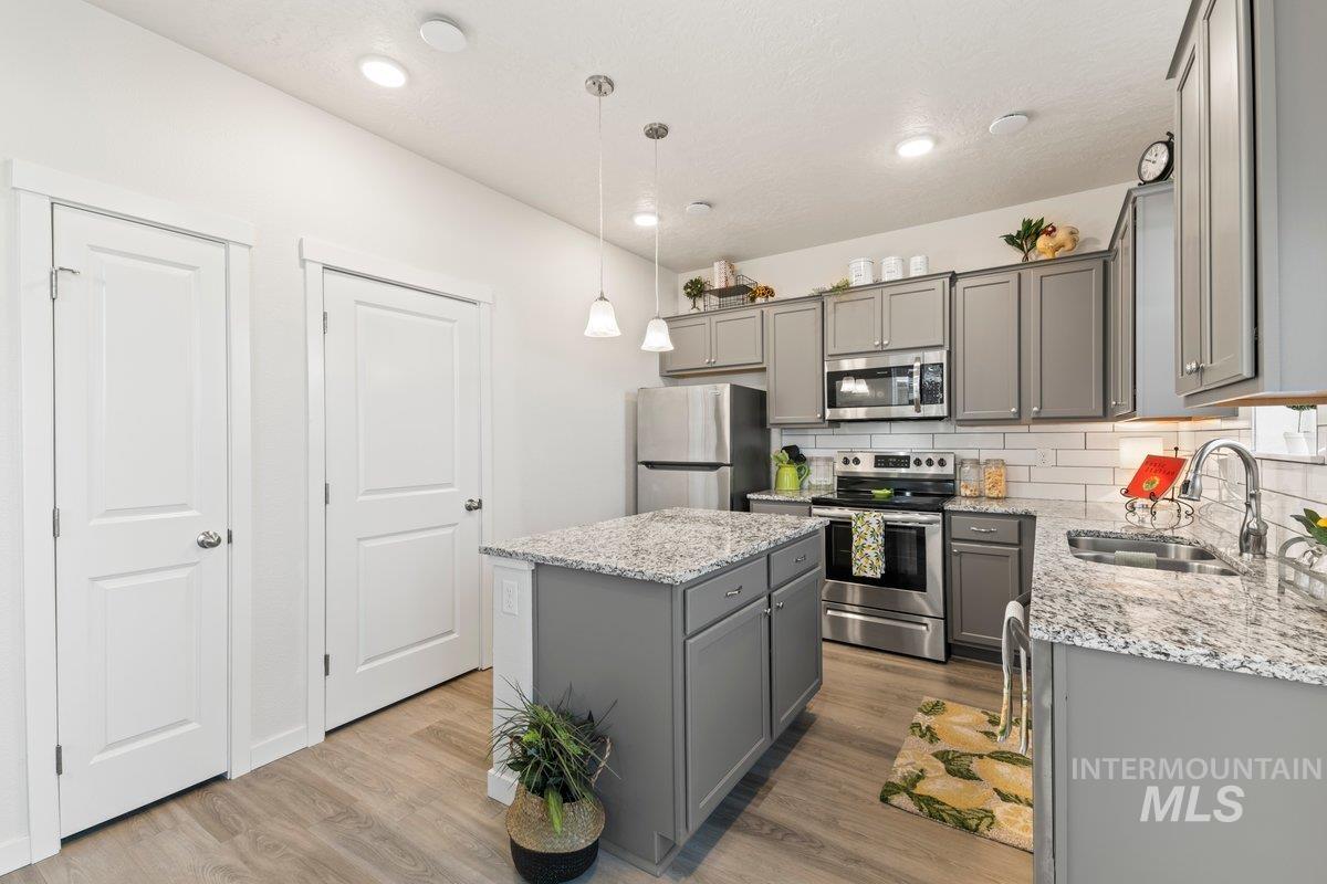 Kitchen with tasteful backsplash, gray cabinets, stainless steel appliances, a center island, and recessed lighting