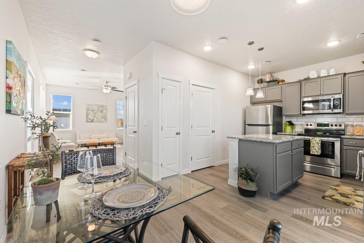Kitchen with gray cabinetry, stainless steel appliances, a kitchen island, light stone countertops, and a textured ceiling