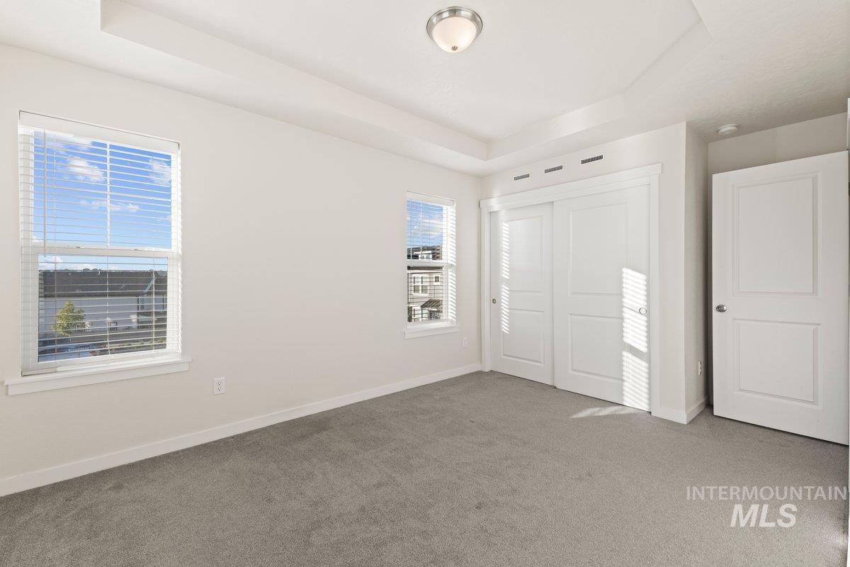 Unfurnished bedroom with a raised ceiling, carpet, and a closet