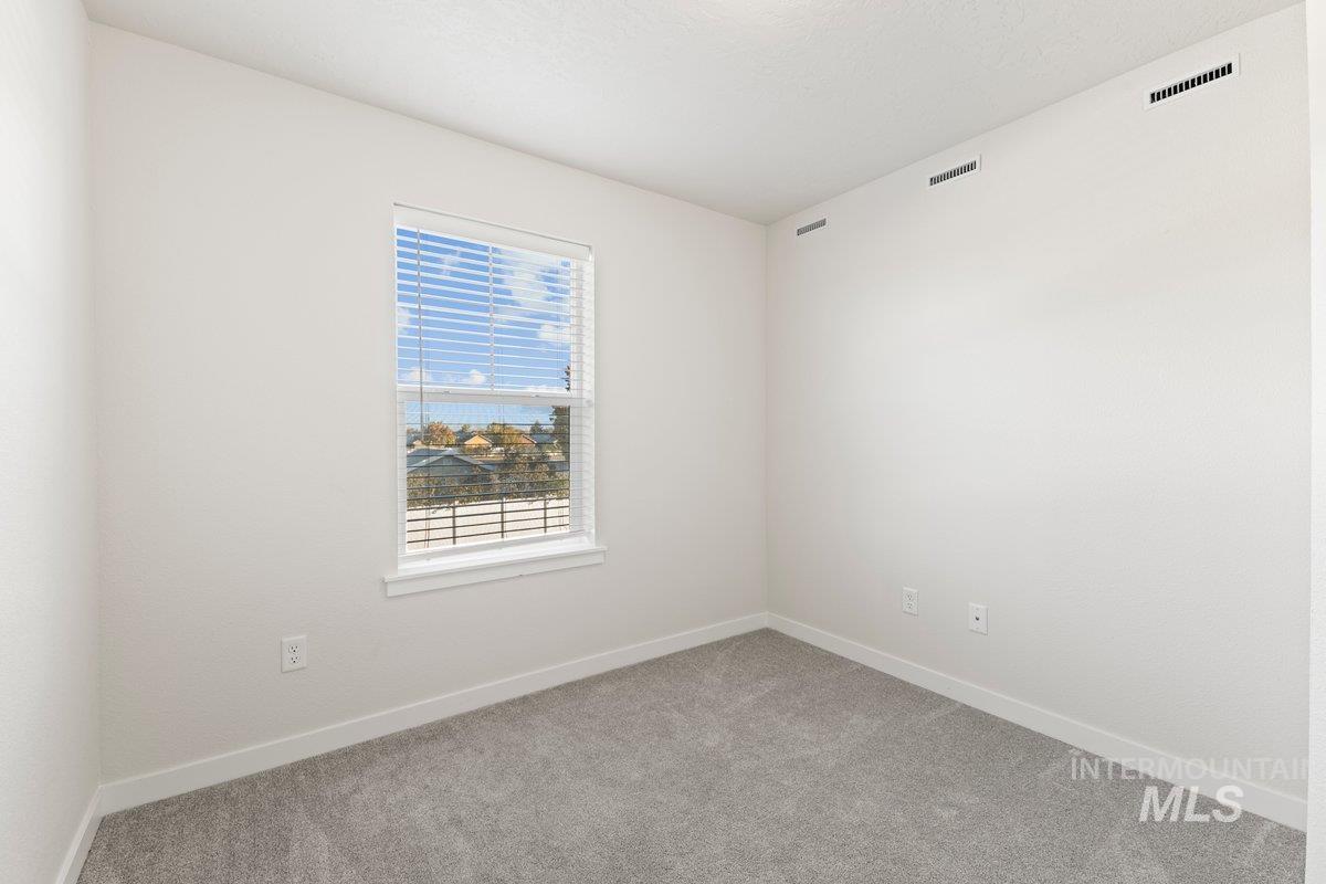 Spare room featuring light colored carpet and baseboards