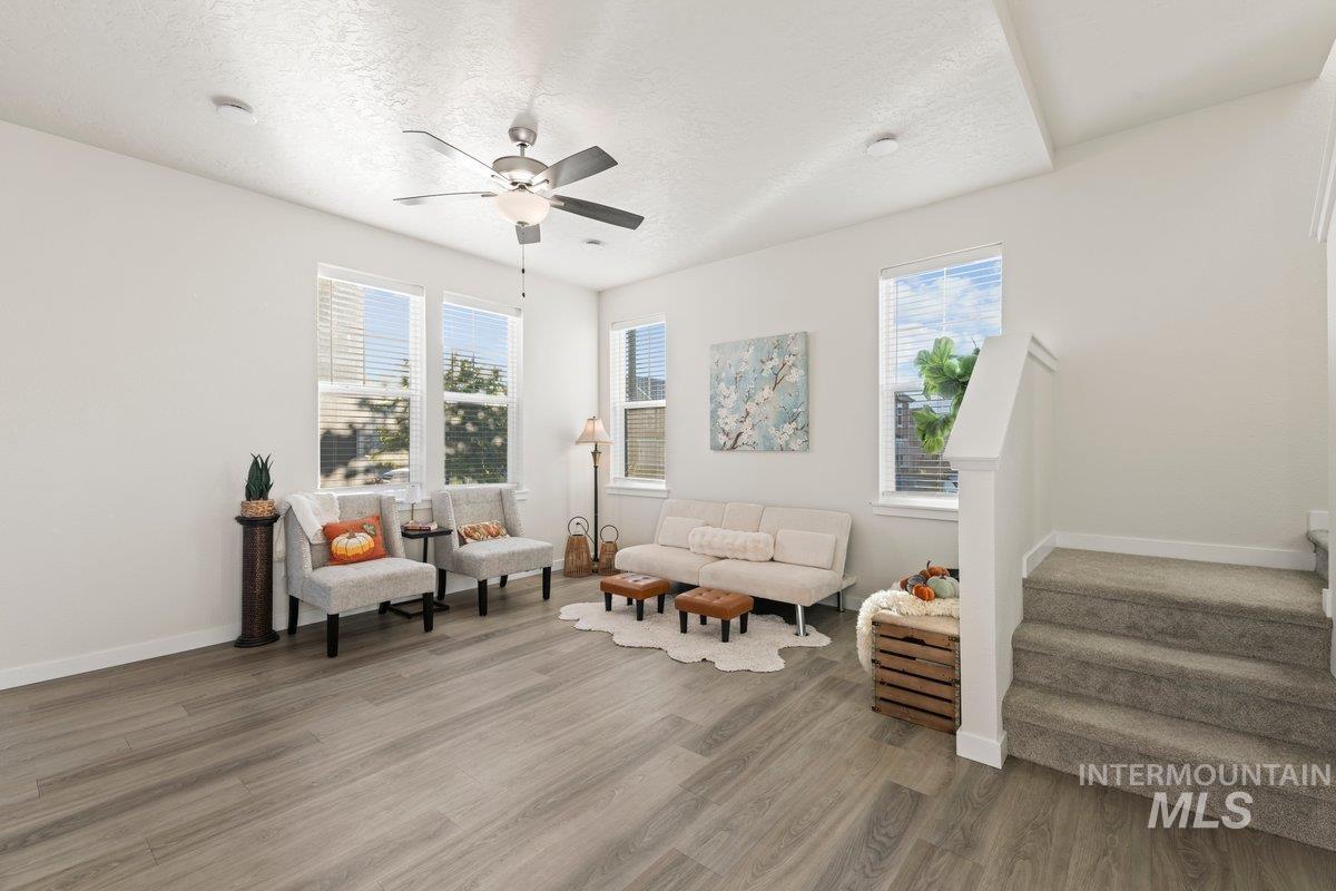 Sitting room with a textured ceiling, light wood finished floors, stairs, and ceiling fan