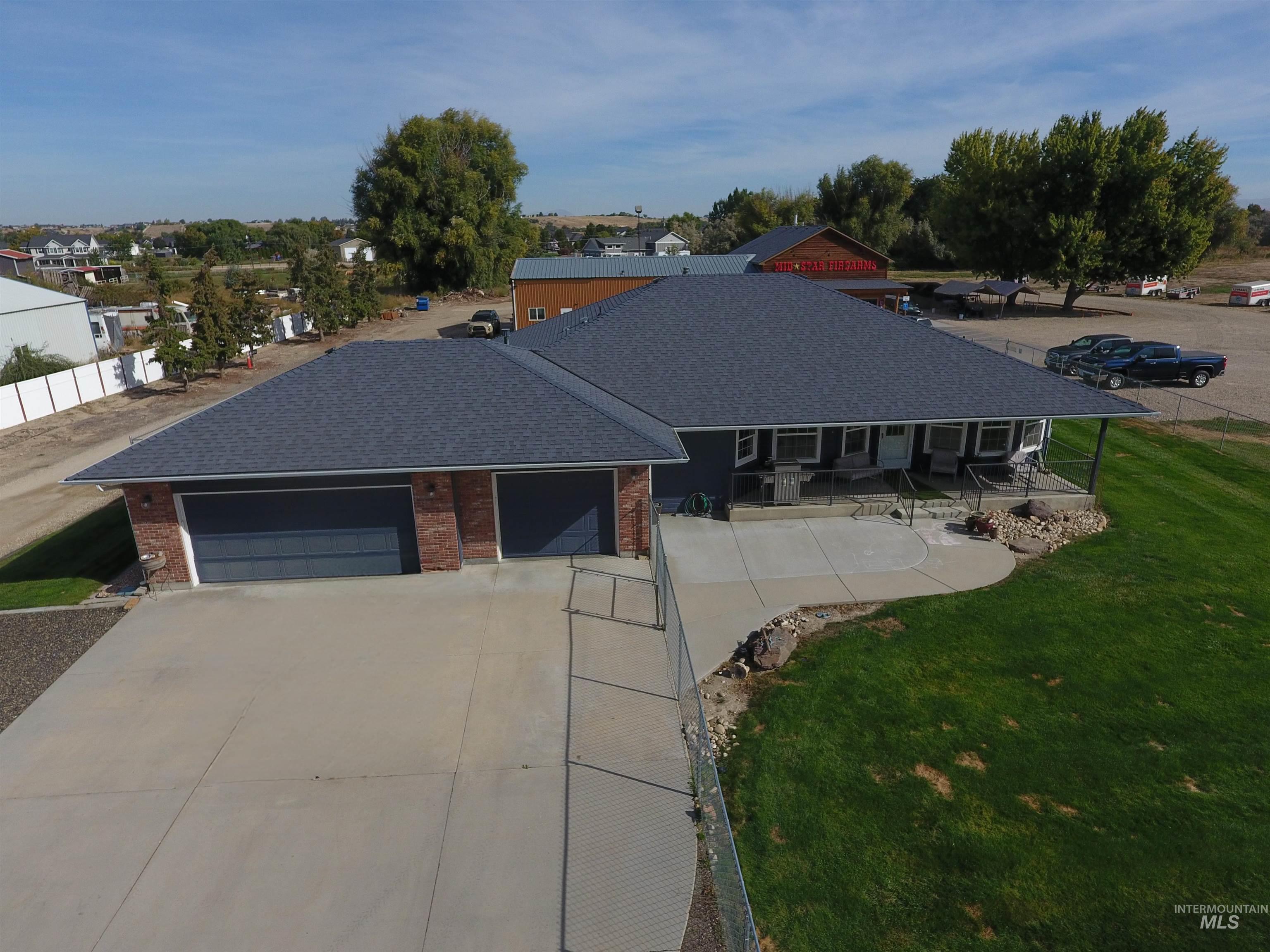 Single story home featuring a shingled roof, a garage, brick siding, concrete driveway, and a patio