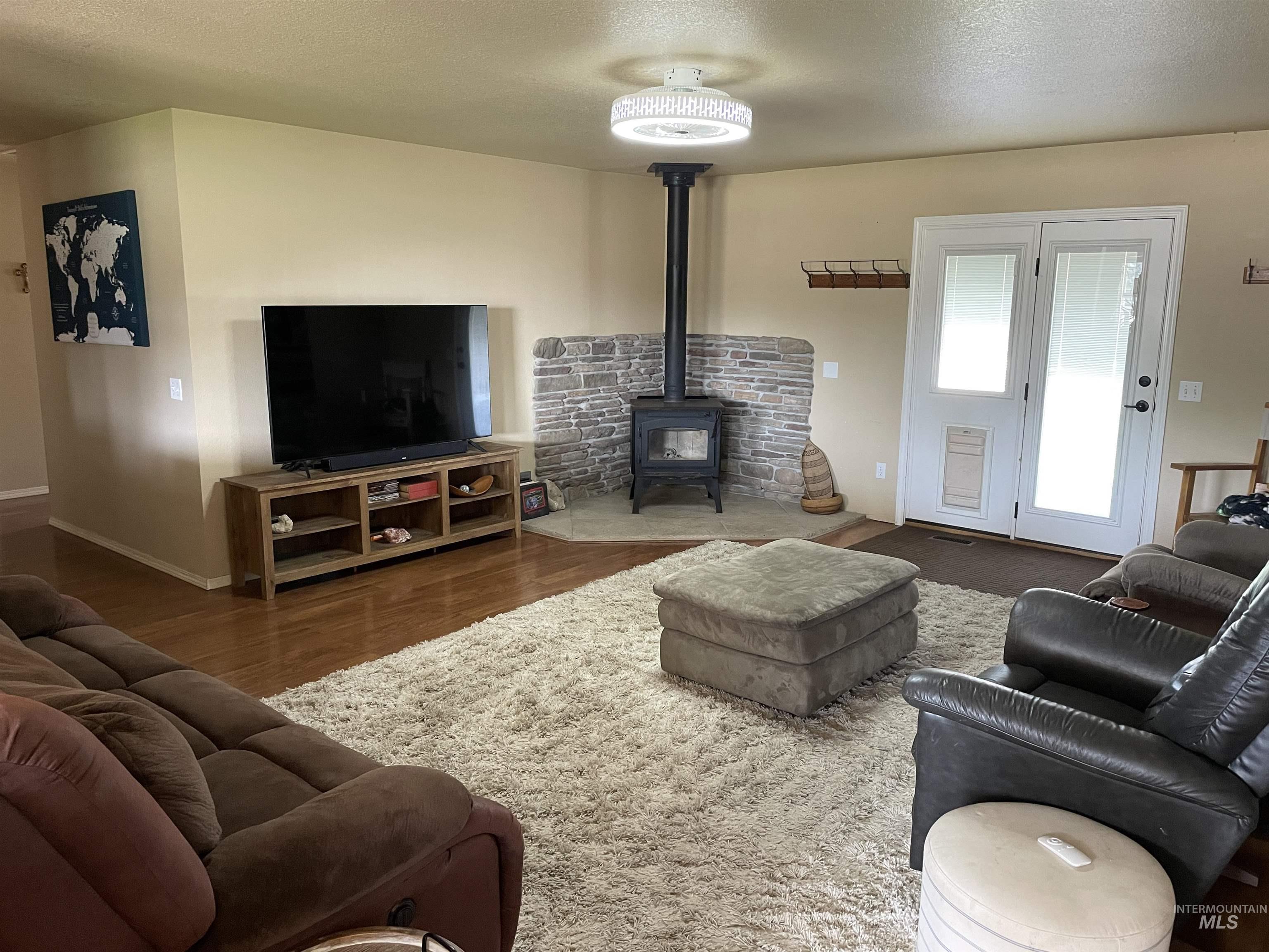 Living room featuring a wood stove, a textured ceiling, and wood finished floors