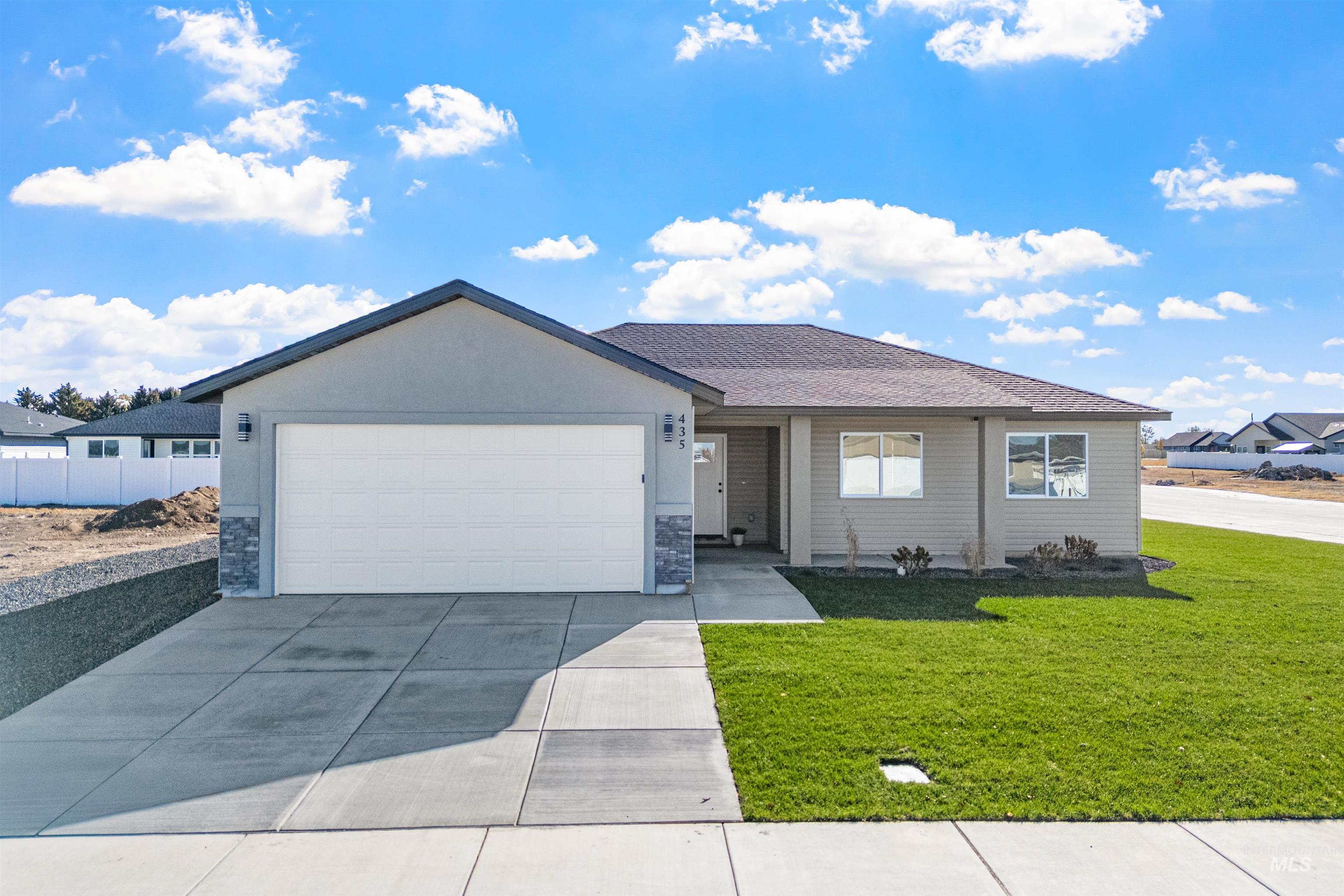 Ranch-style home featuring stone siding, a front lawn, concrete driveway, and an attached garage