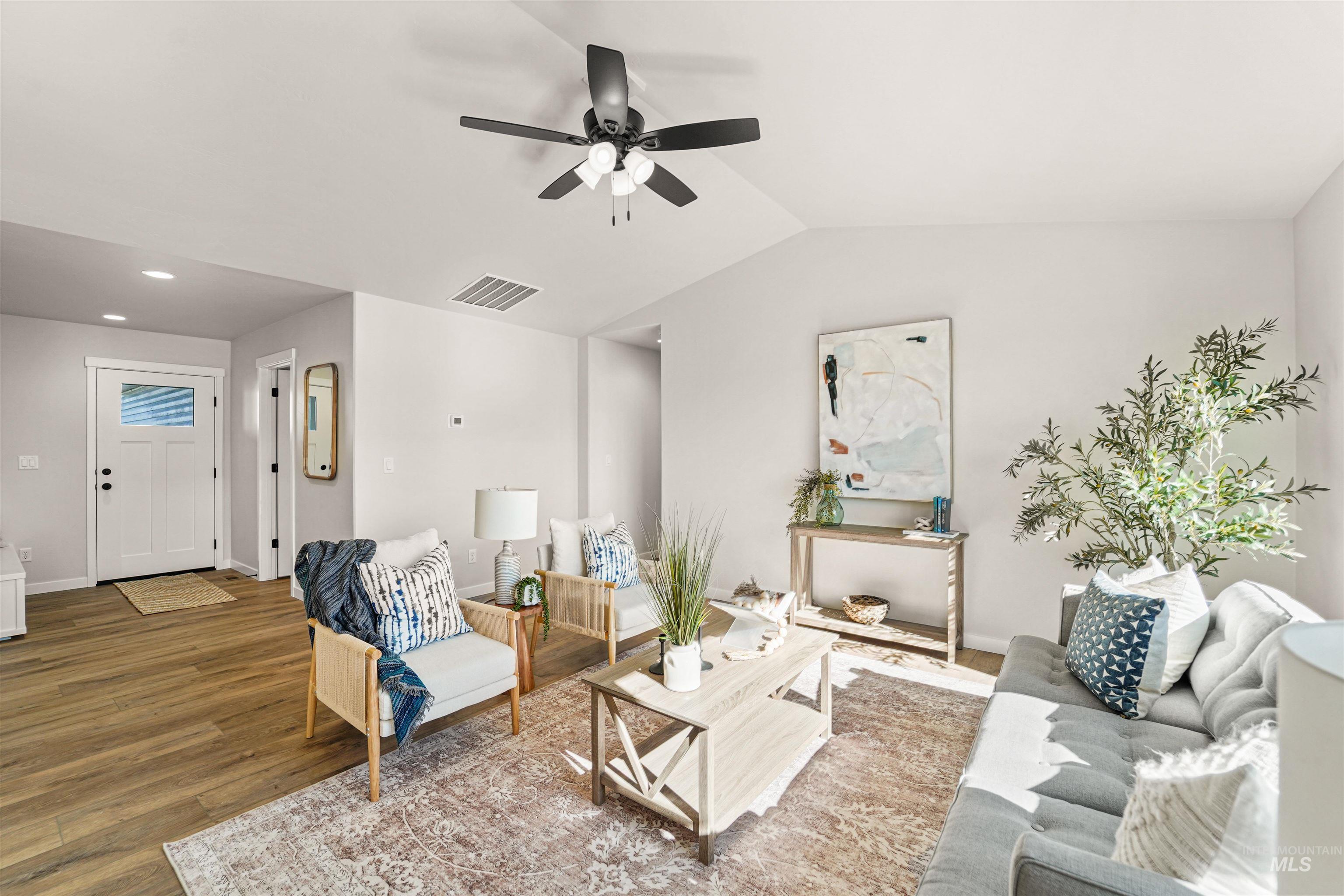 Living room with wood finished floors, lofted ceiling, and a ceiling fan
