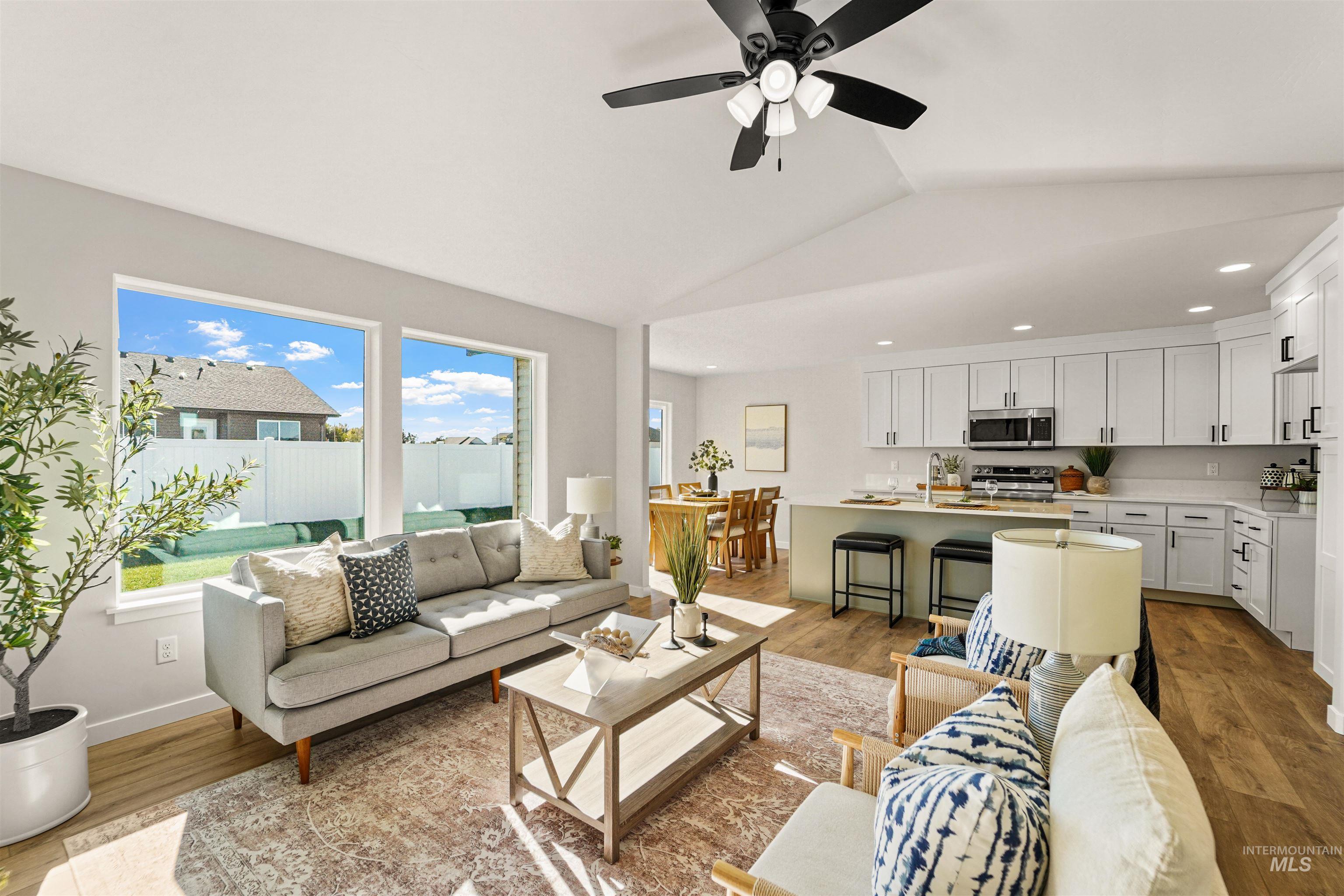 Living area featuring light wood-style flooring, lofted ceiling, ceiling fan, and recessed lighting