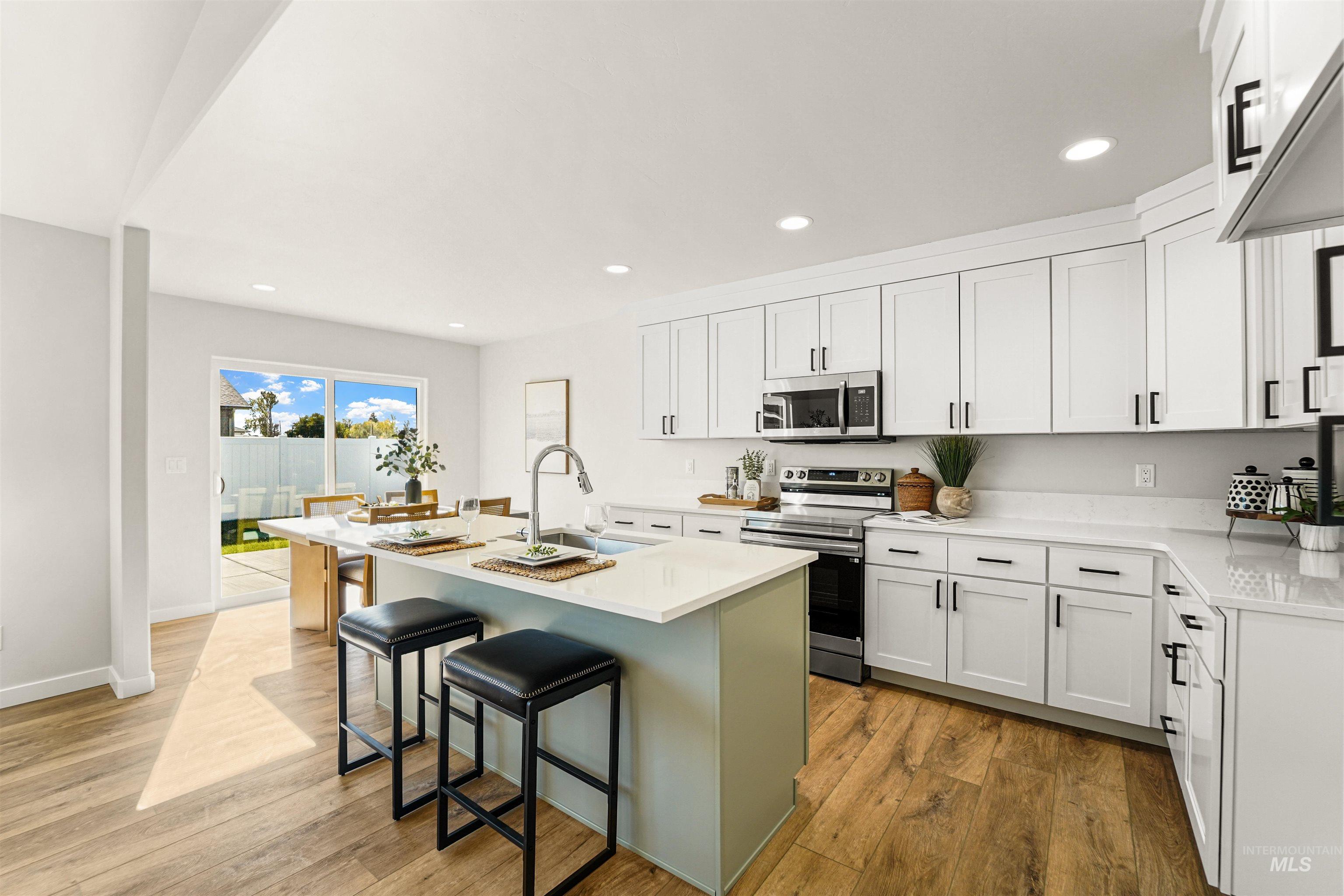 Kitchen with appliances with stainless steel finishes, white cabinets, light wood-style flooring, and recessed lighting