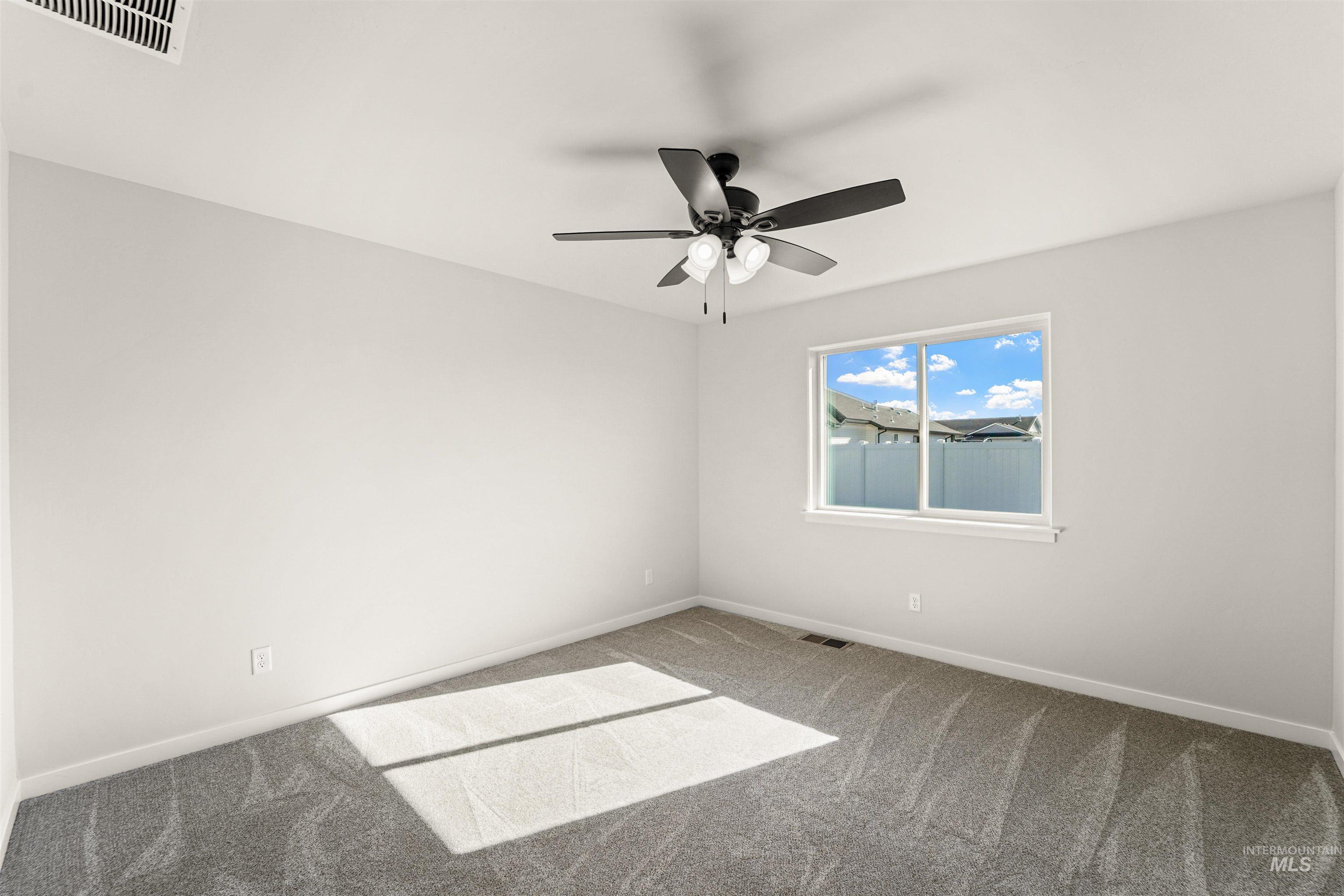 Empty room with carpet floors and a ceiling fan
