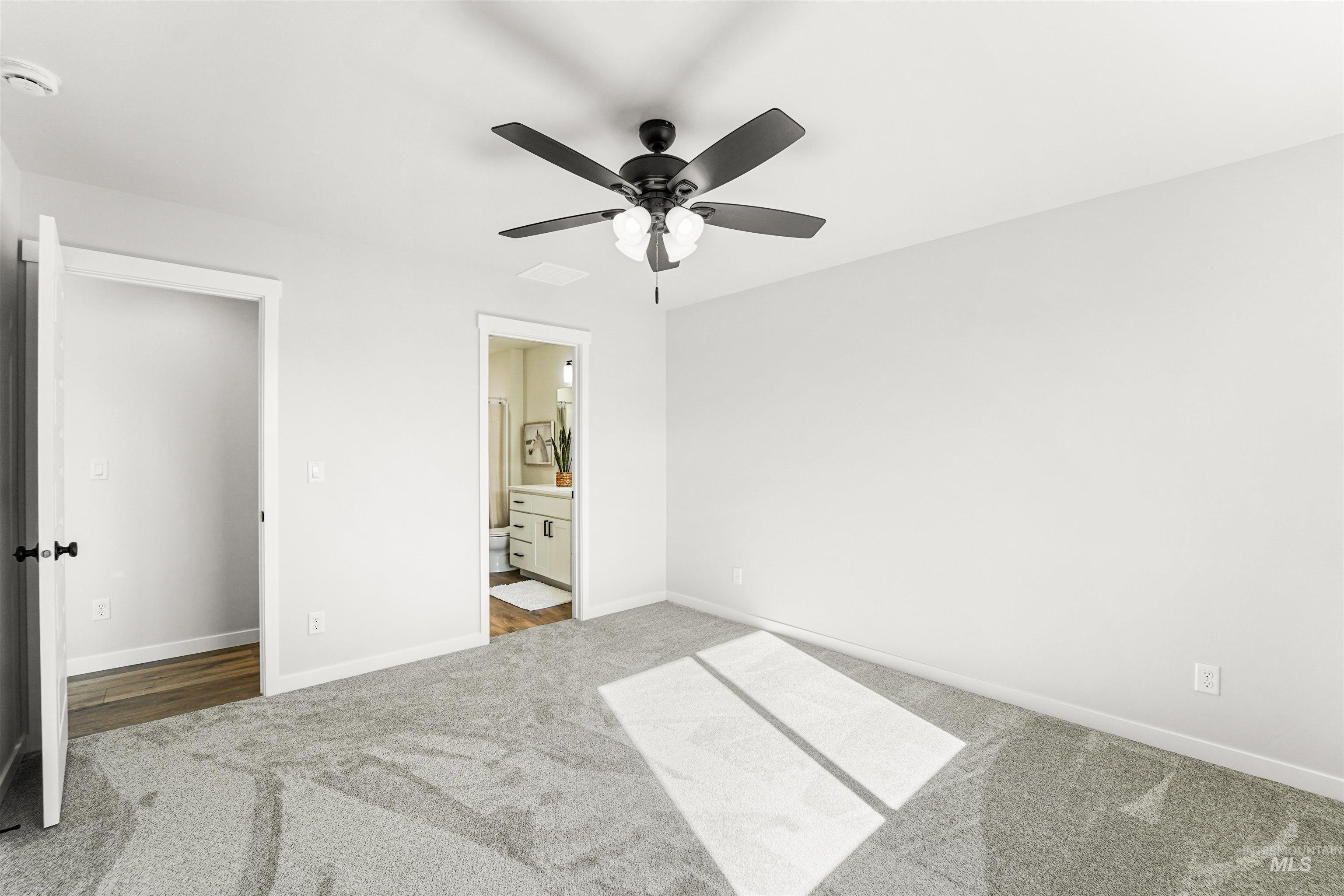 Unfurnished bedroom with carpet, connected bathroom, and ceiling fan