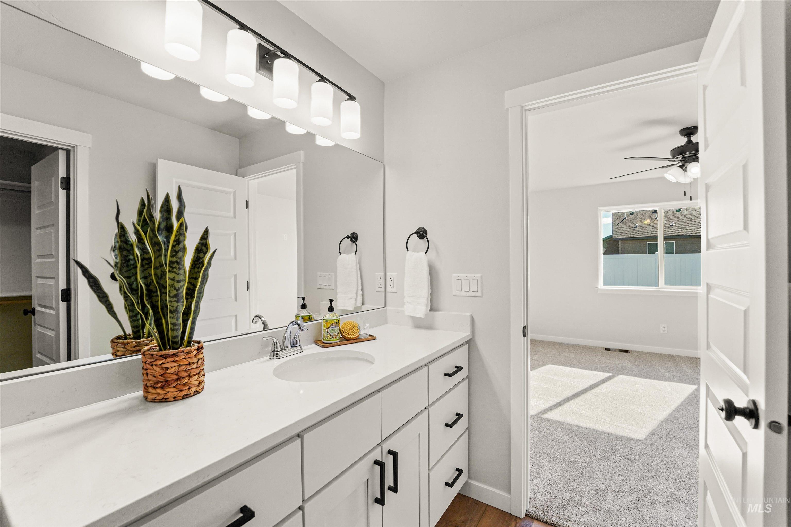 Bathroom with vanity, dark colored carpet, ceiling fan, and dark wood-style floors