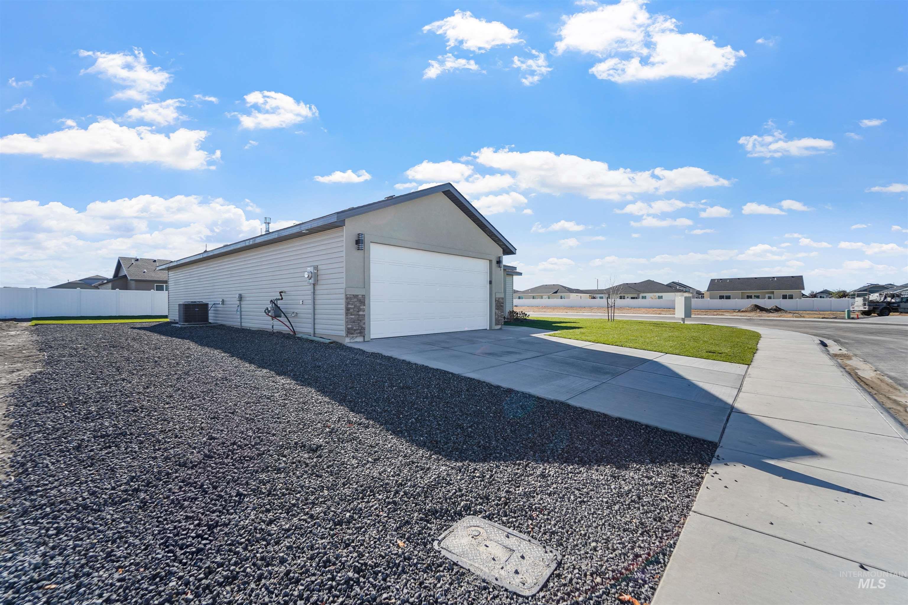View of side of home with a garage, an outdoor structure, concrete driveway, and a residential view