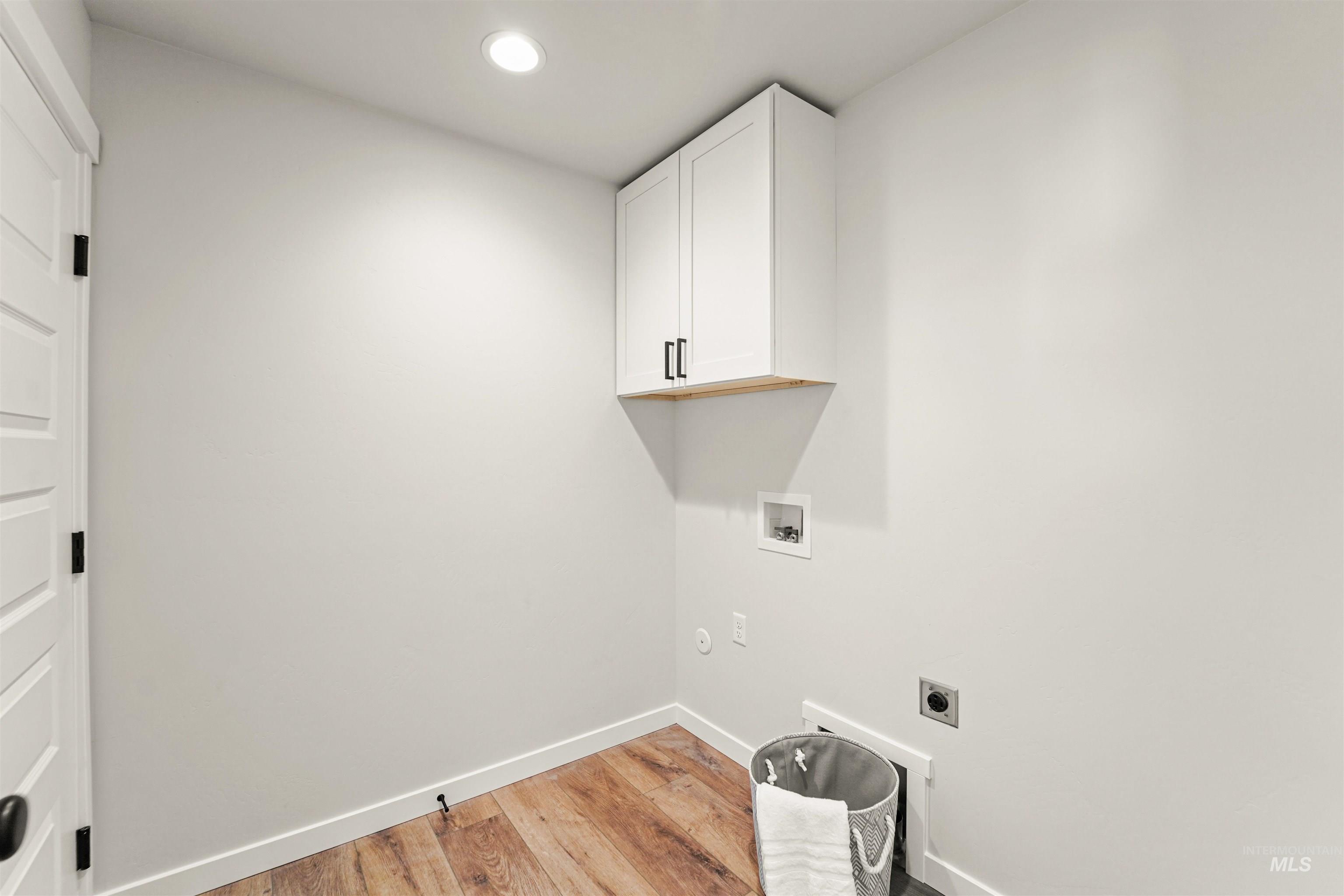 Washroom with light wood-style flooring, hookup for an electric dryer, washer hookup, recessed lighting, and cabinet space