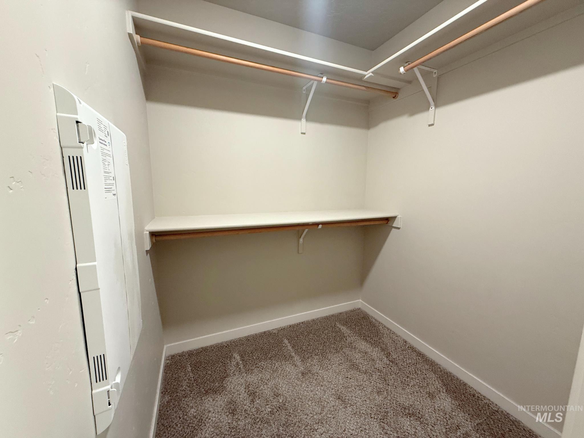 Walk in closet with carpet floors and a heating unit
