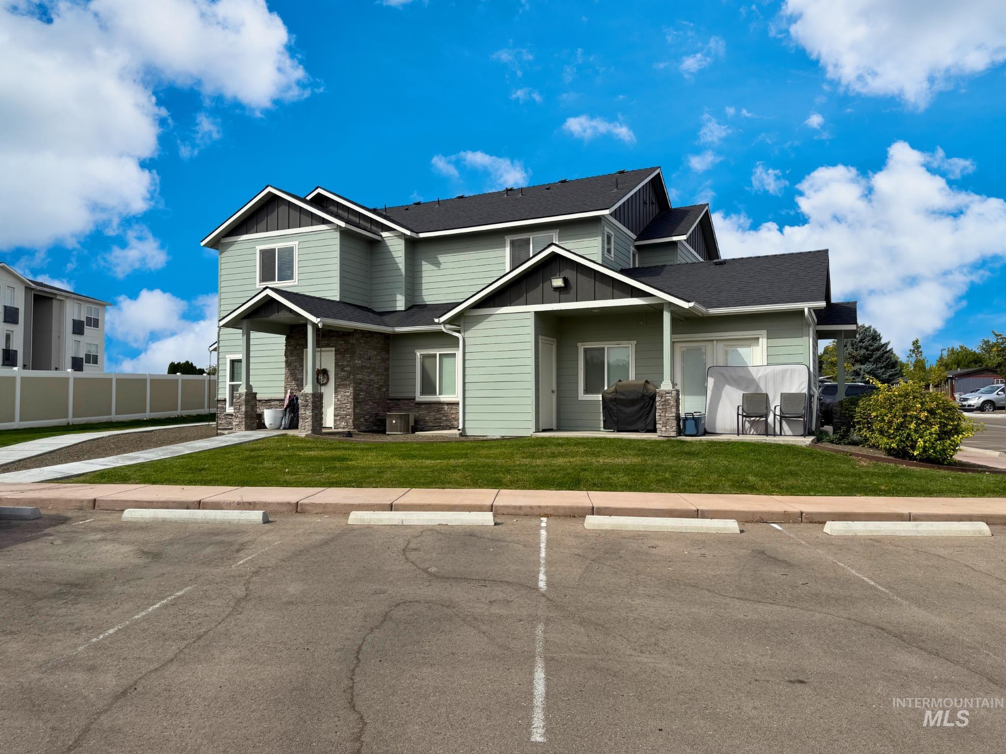 View of front of house featuring board and batten siding, uncovered parking, and stone siding