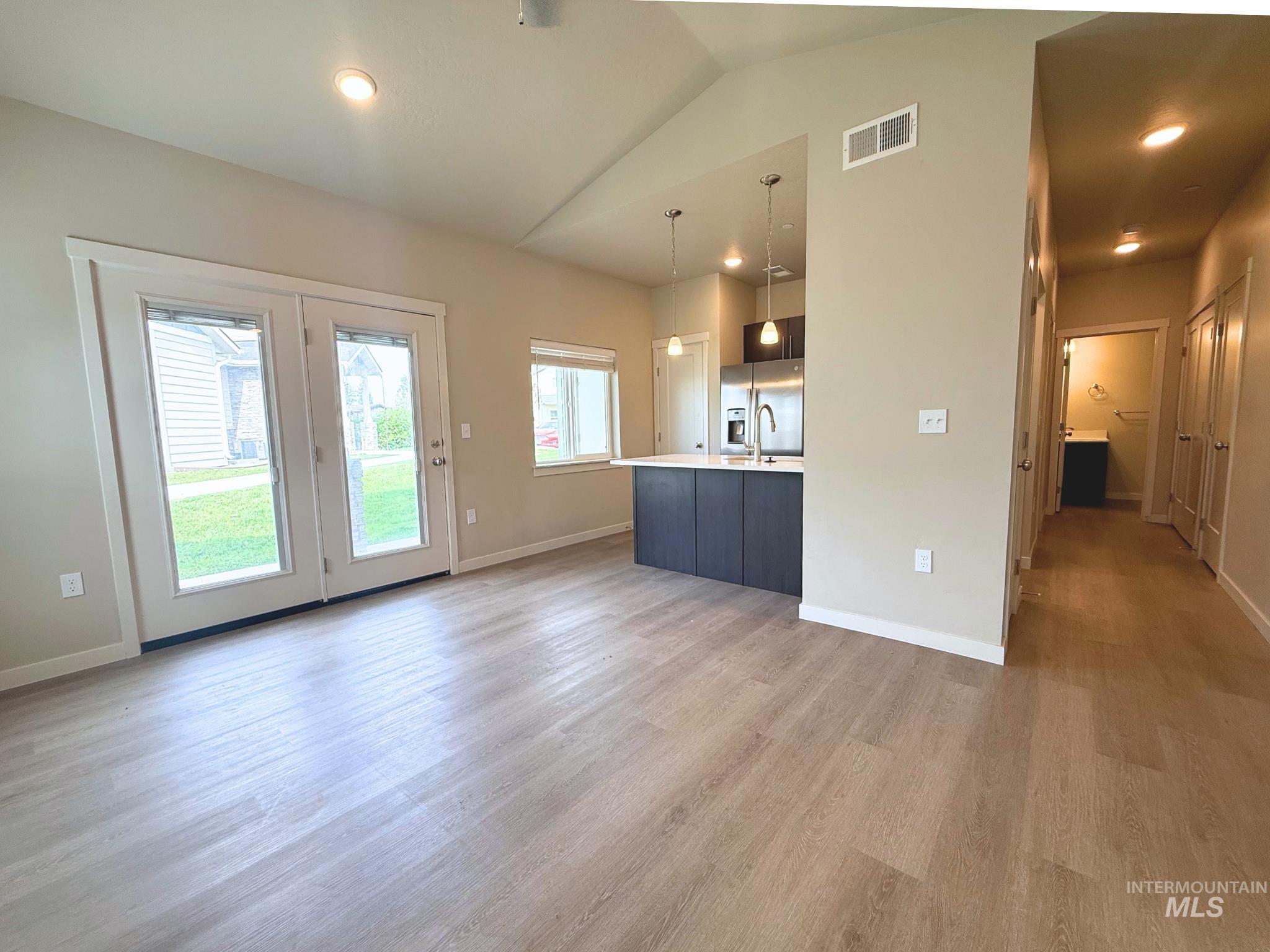 Unfurnished living room with vaulted ceiling, light wood-style flooring, and recessed lighting