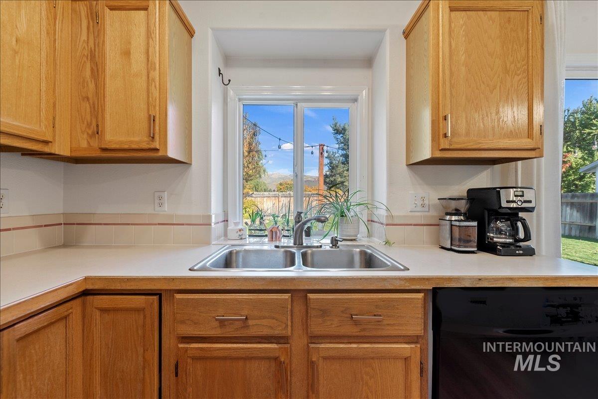 Kitchen featuring light countertops, black dishwasher, and brown cabinets