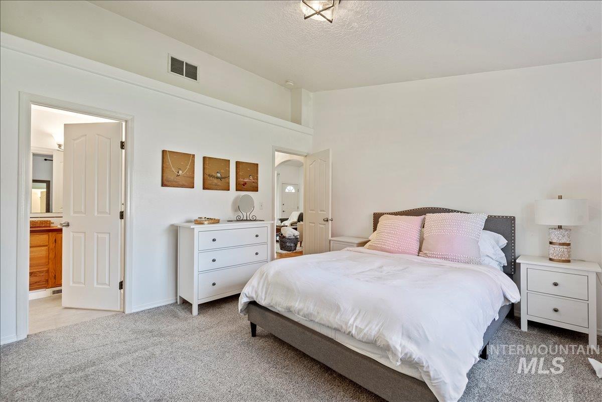 Bedroom featuring light carpet, connected bathroom, and a textured ceiling
