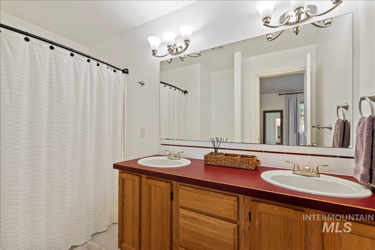 Full bathroom with a chandelier, double vanity, and curtained shower