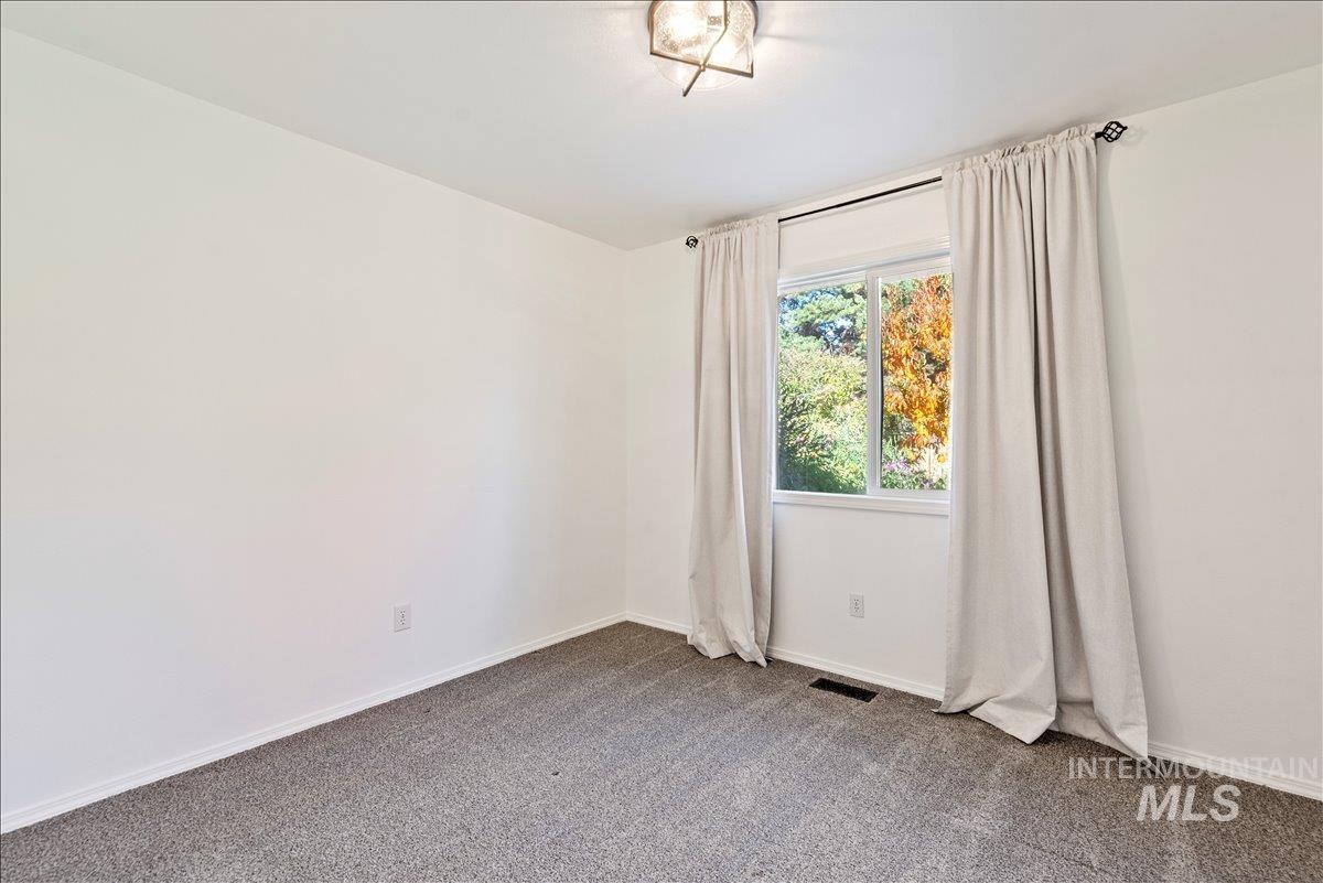 Empty room featuring carpet flooring and baseboards